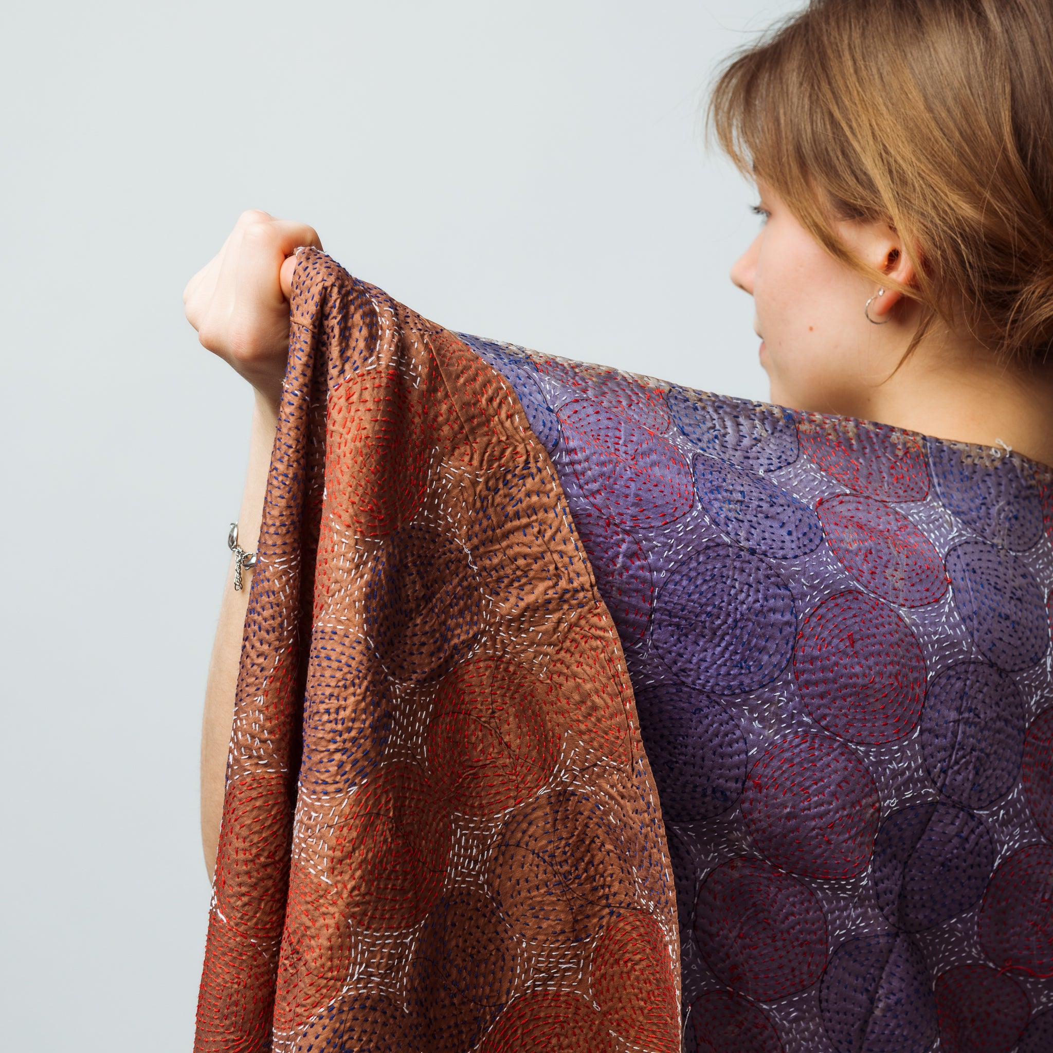 Person wearing a patterned shawl with a neutral background