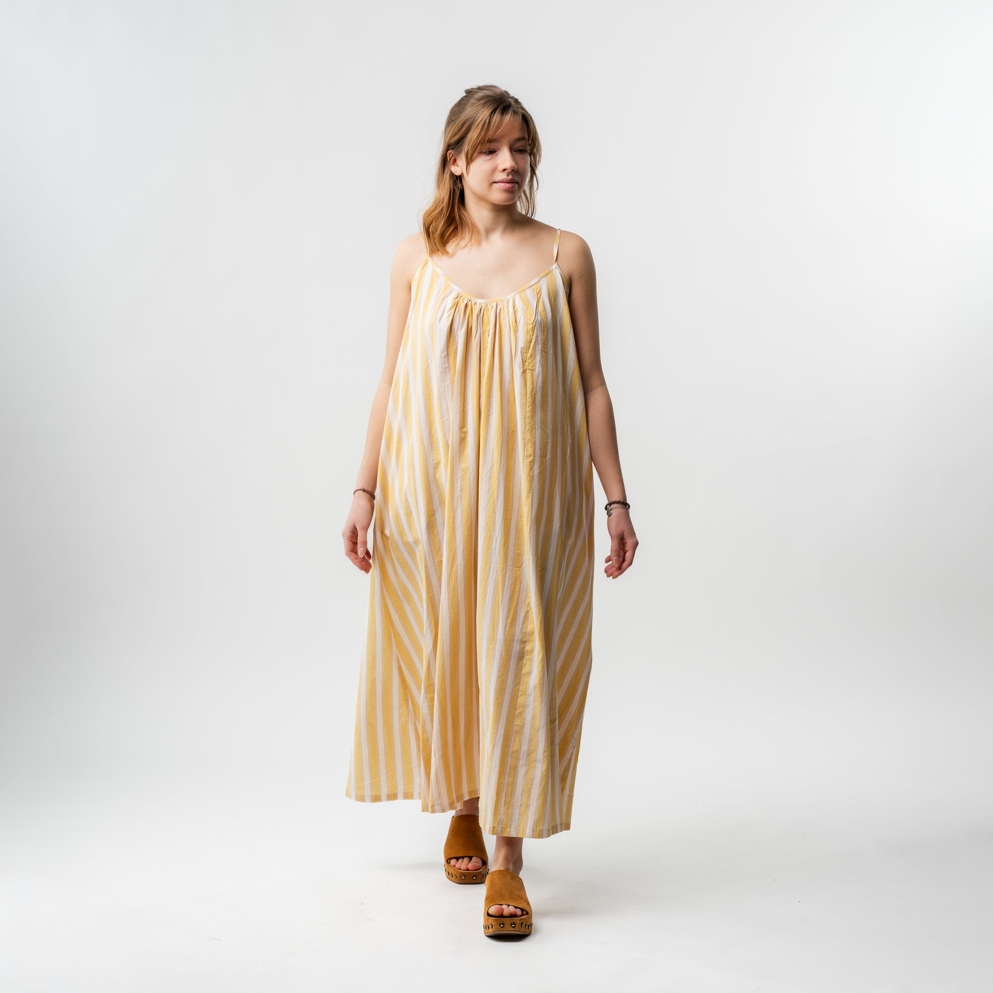 Woman wearing a yellow and white striped dress on a white background
