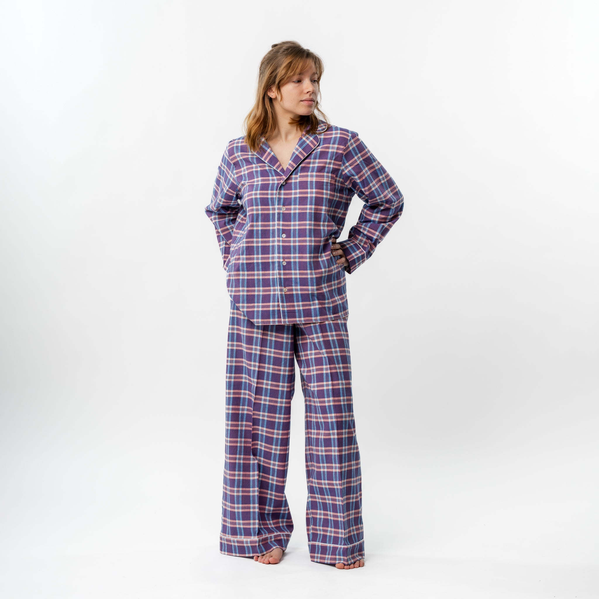 Woman wearing a blue and pink plaid pajama set on a white background