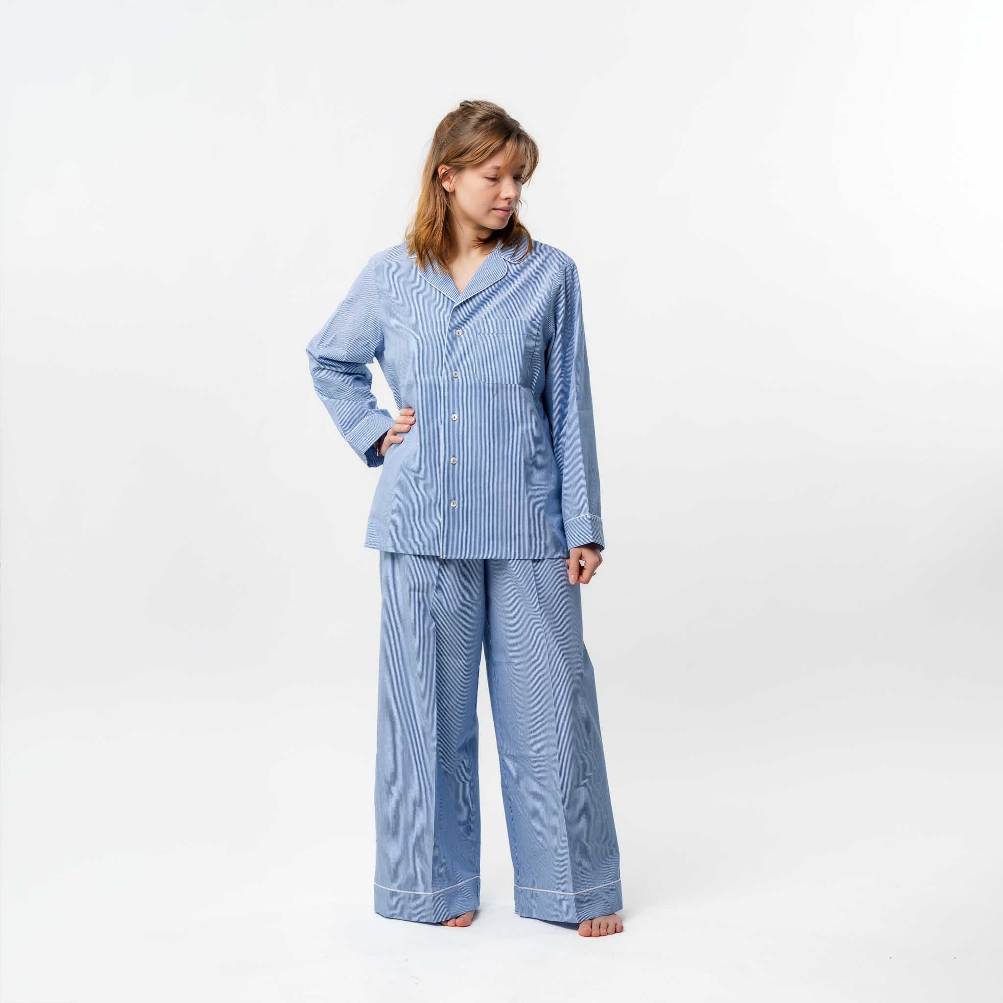 Woman wearing a blue striped pajama set on a white background