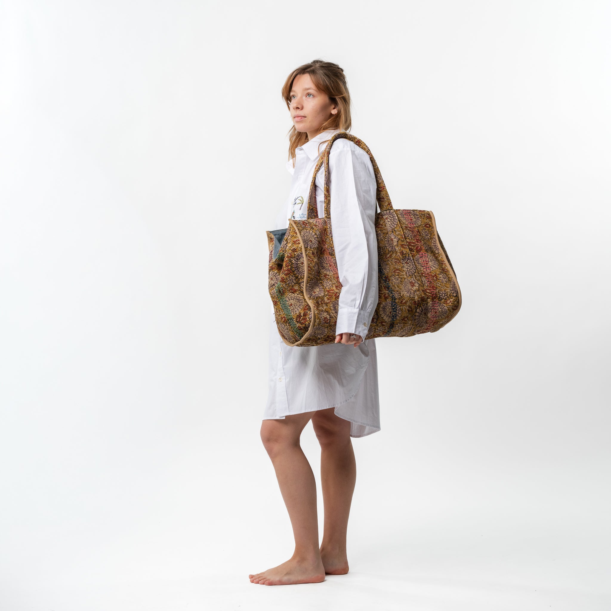 Woman carrying a large patterned tote bag on a white background