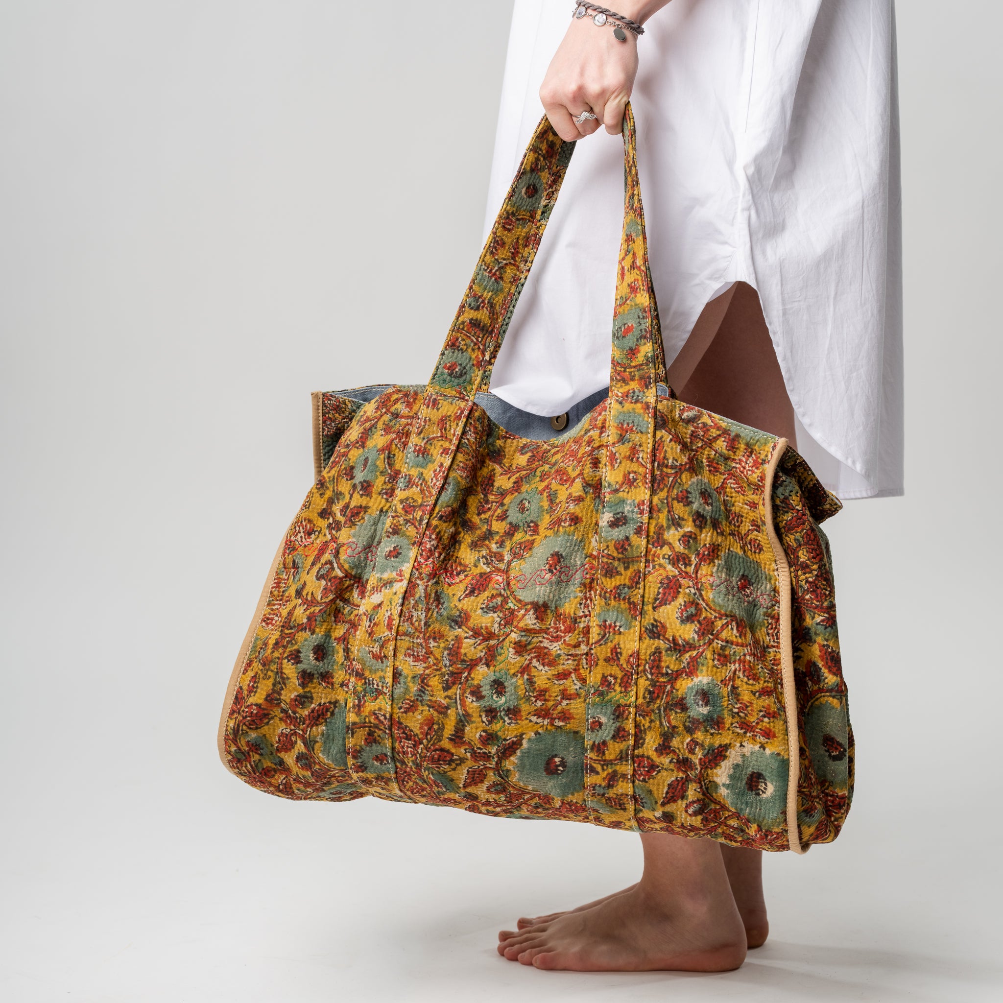 Person holding a large, patterned bag against a plain background