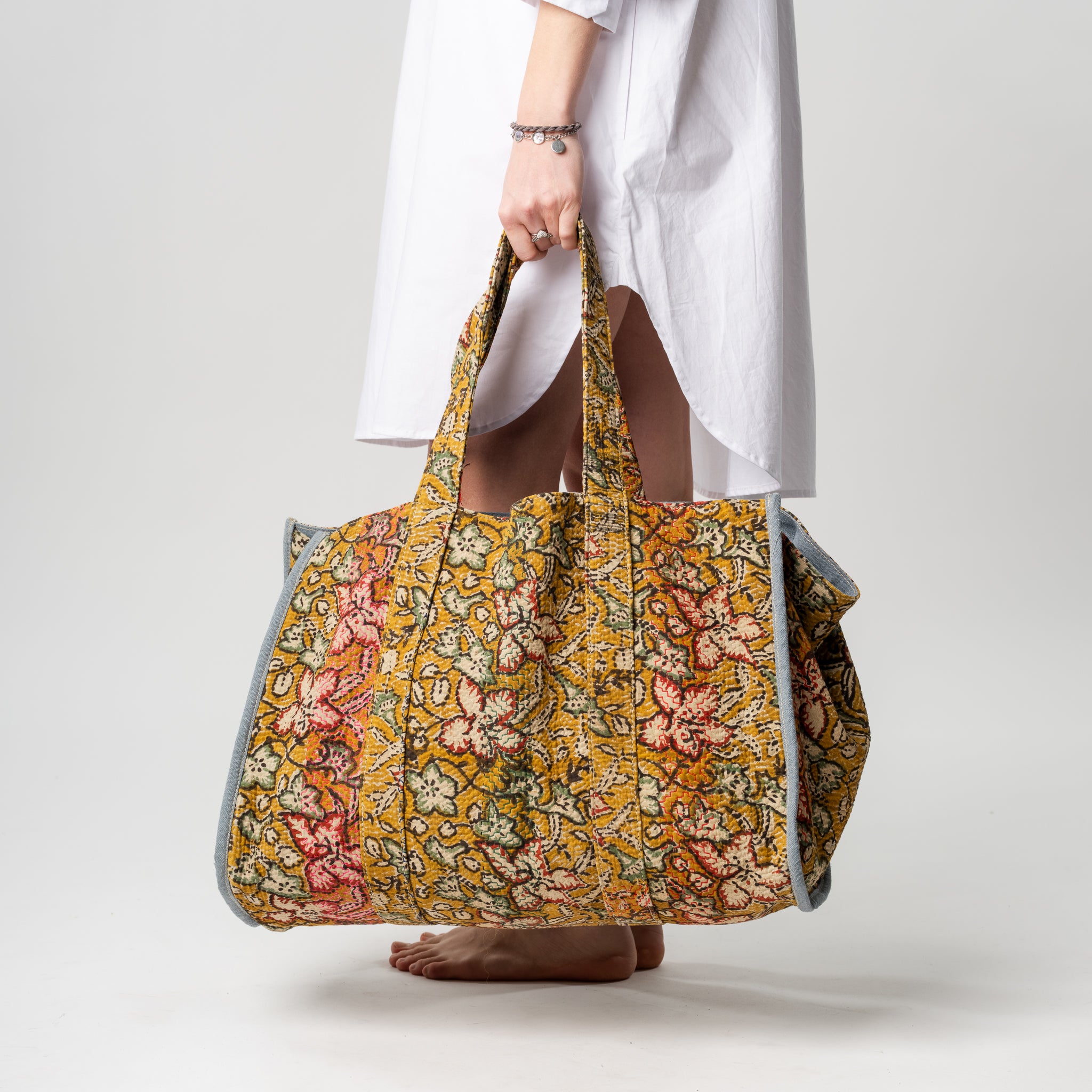 Person holding a floral patterned bag on a plain background