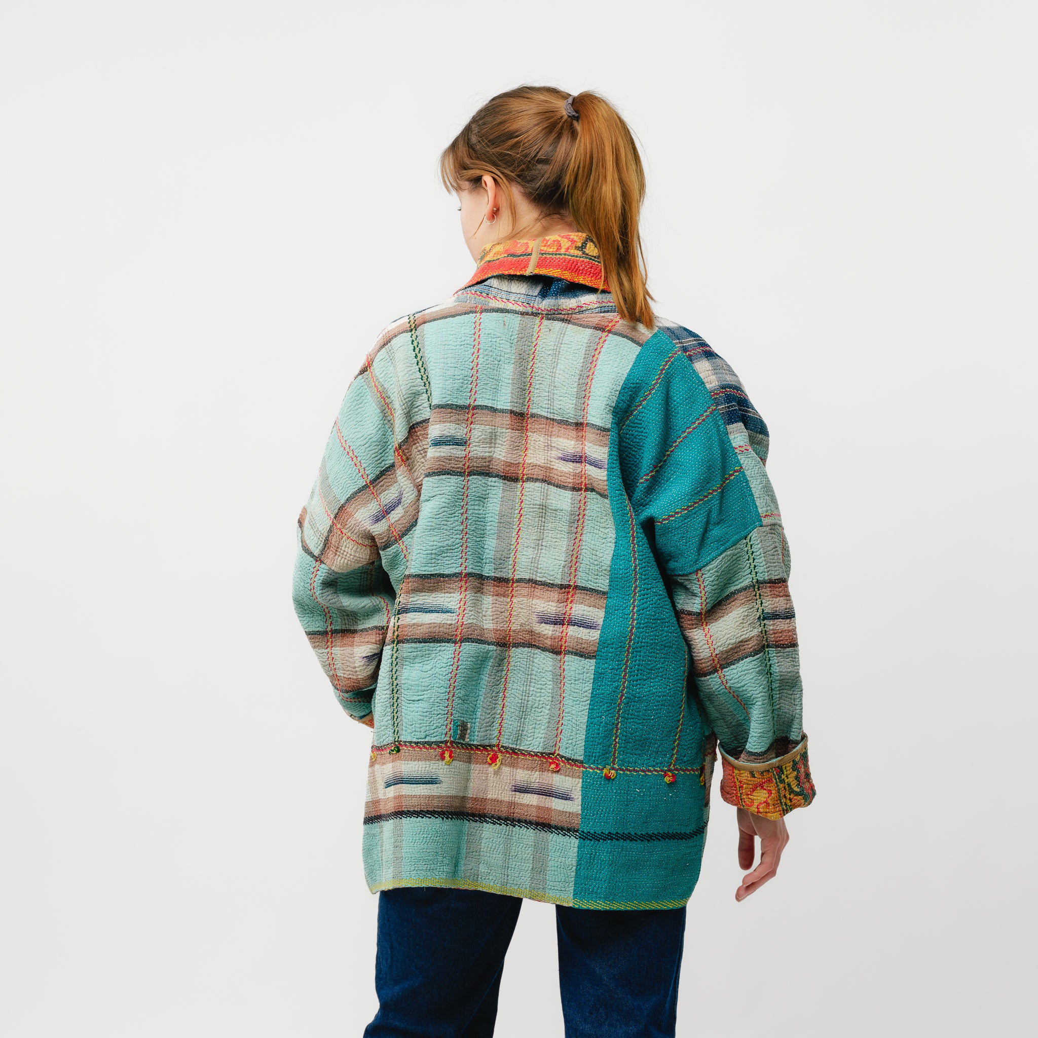 Person wearing a colorful plaid jacket on a white background