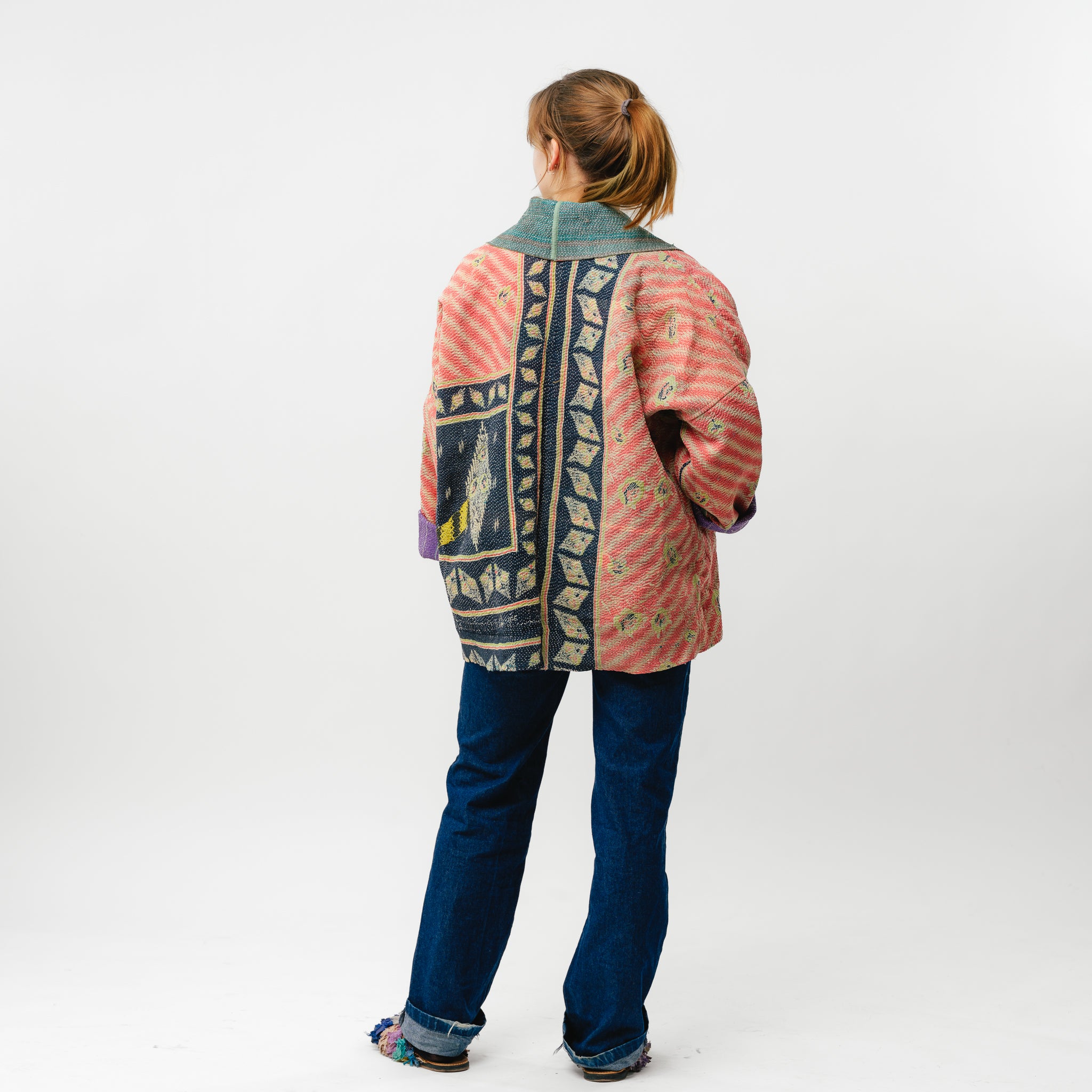 Person wearing a colorful jacket with a patterned back on a white background