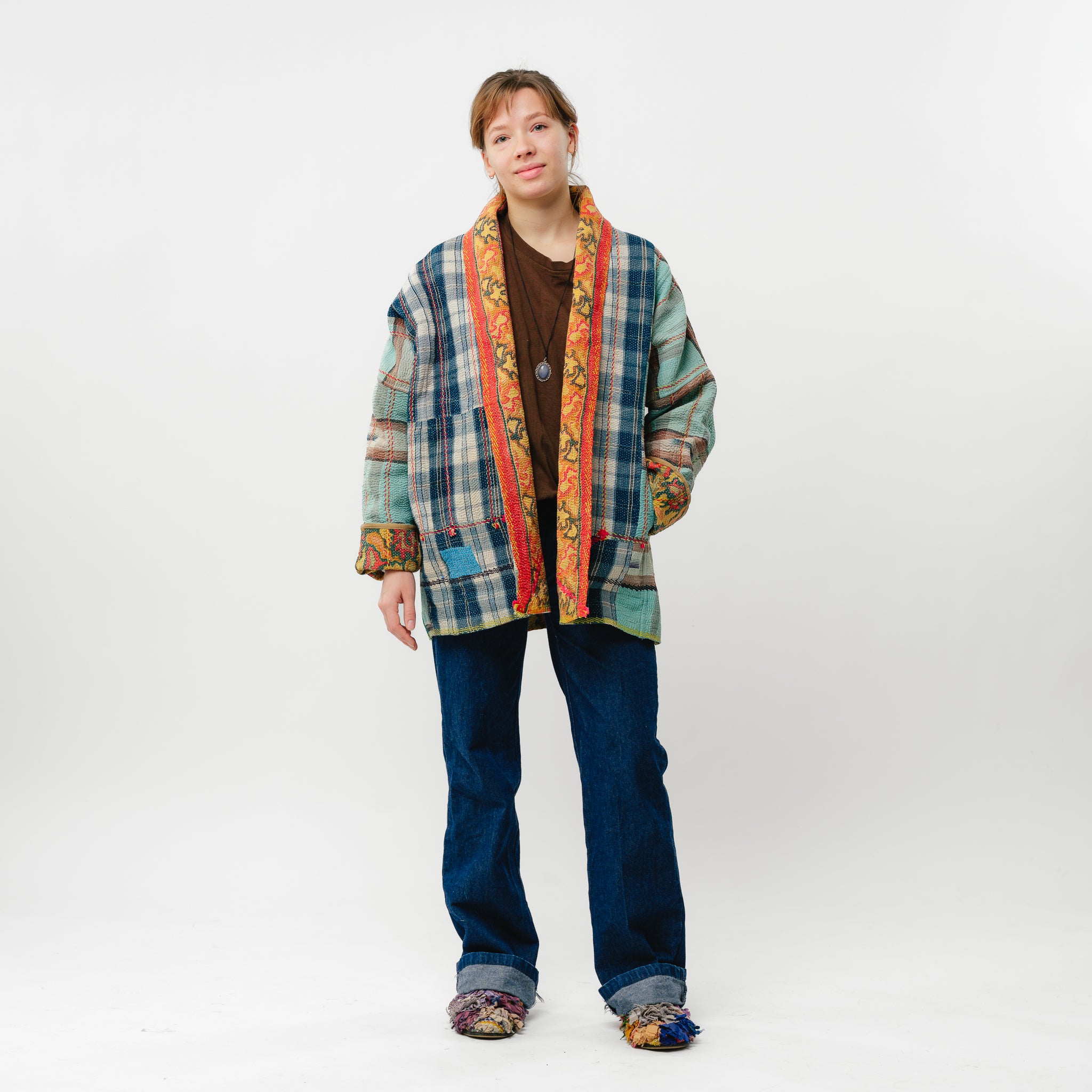 Person wearing a colorful patchwork jacket on a white background