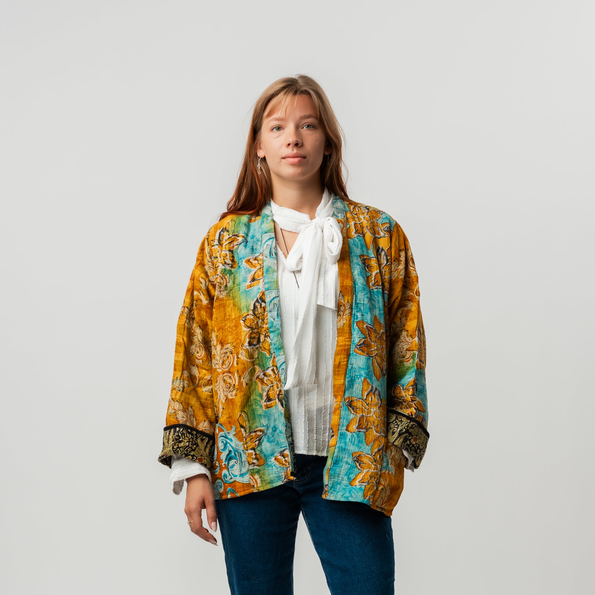 Woman wearing a colorful patterned jacket over a white shirt on a plain background