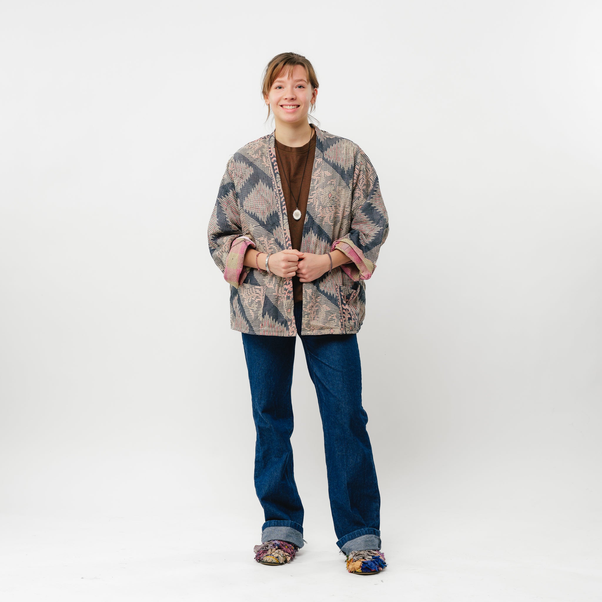 Person wearing a patterned cardigan and jeans on a white background