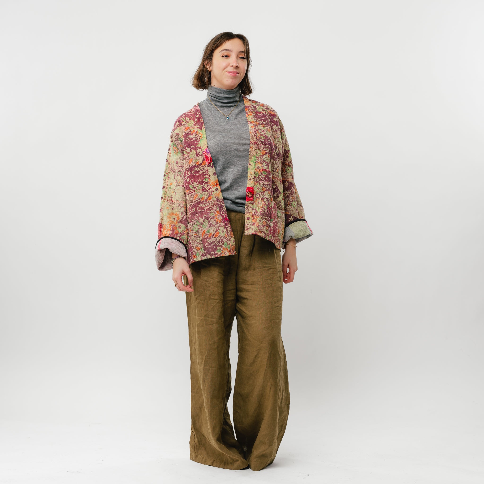 Woman wearing a floral jacket and brown pants on a white background