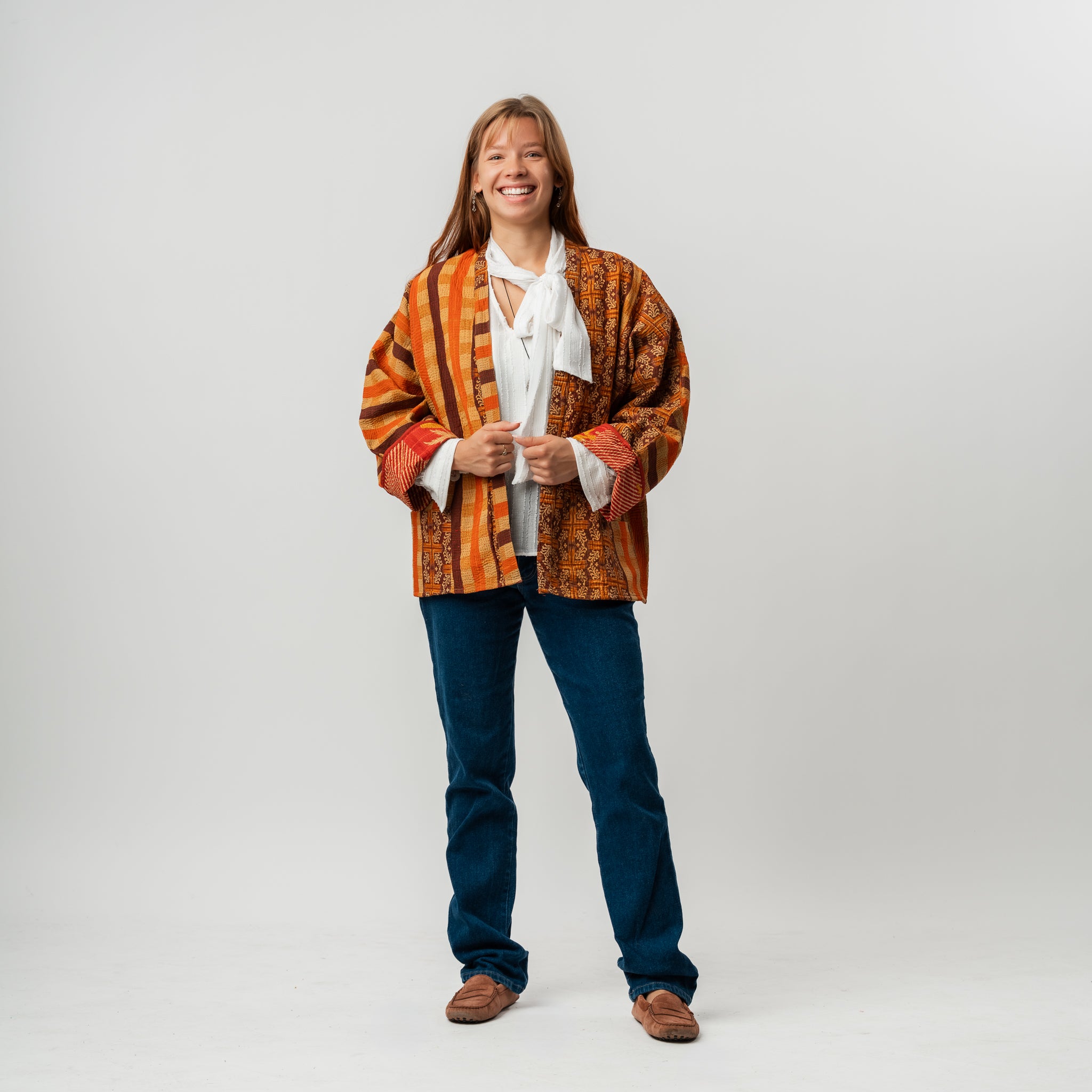 Person wearing a patterned orange and brown jacket on a white background