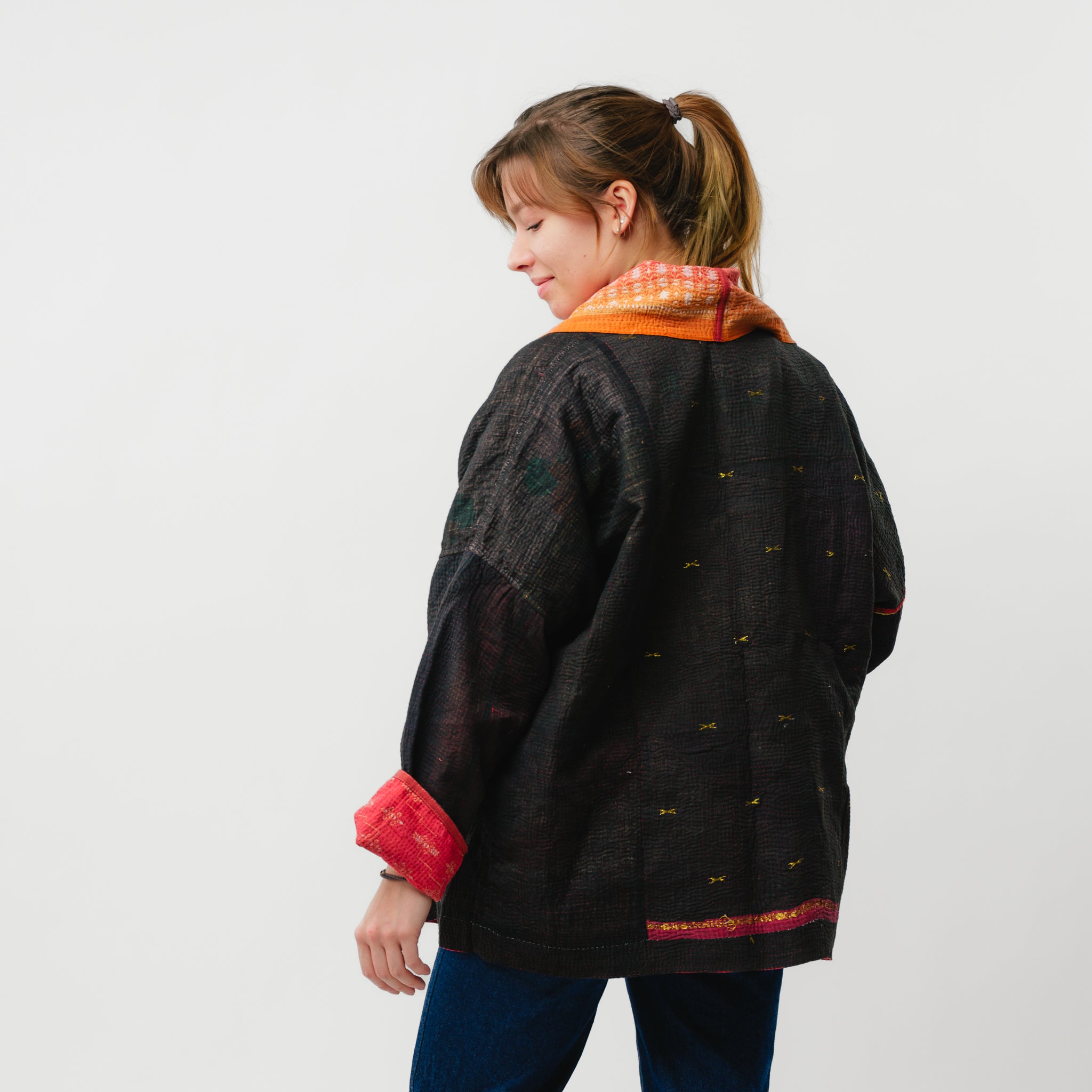 Person wearing a black jacket with colorful accents on a plain background