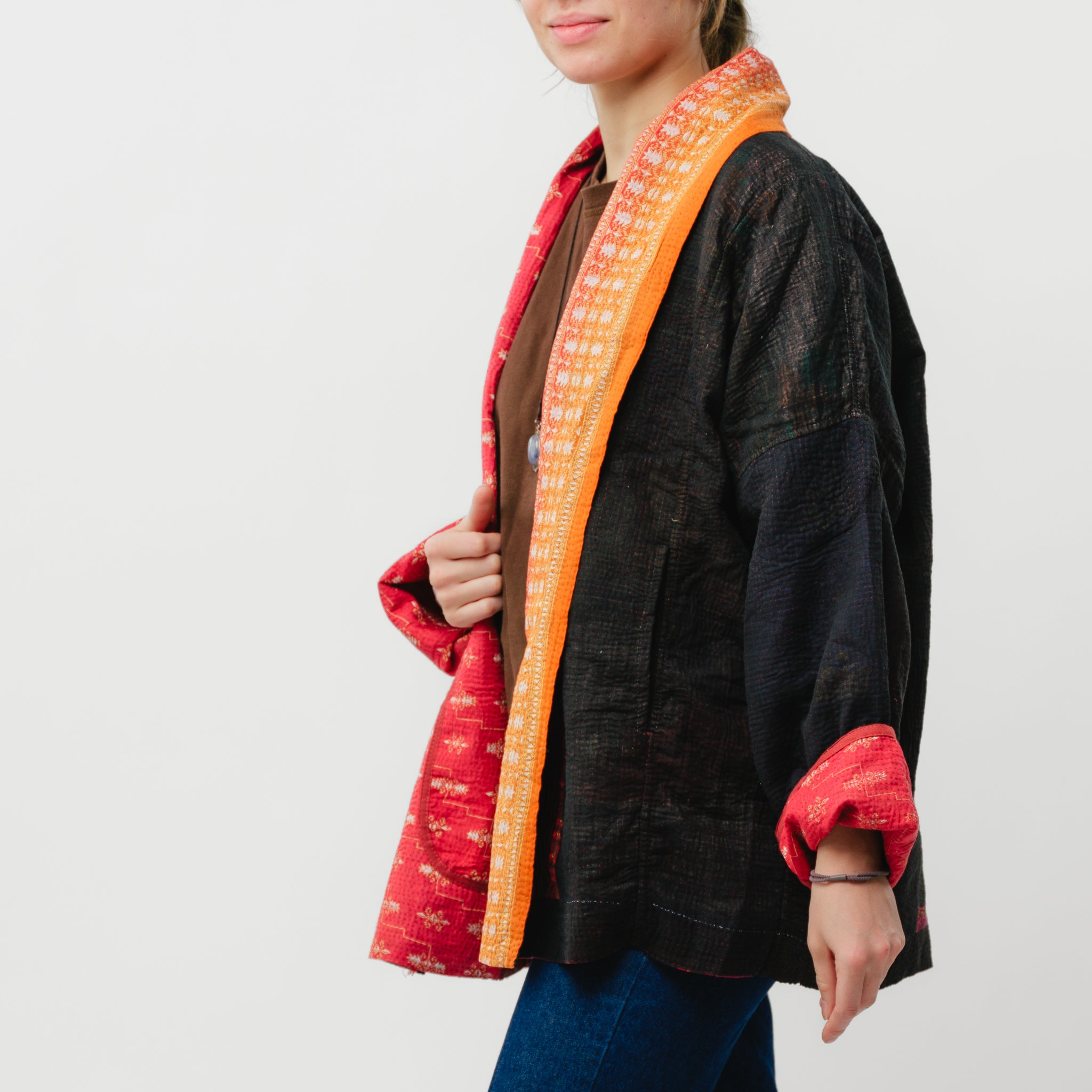 Person wearing a black kimono-style garment with red and orange trim on a white background