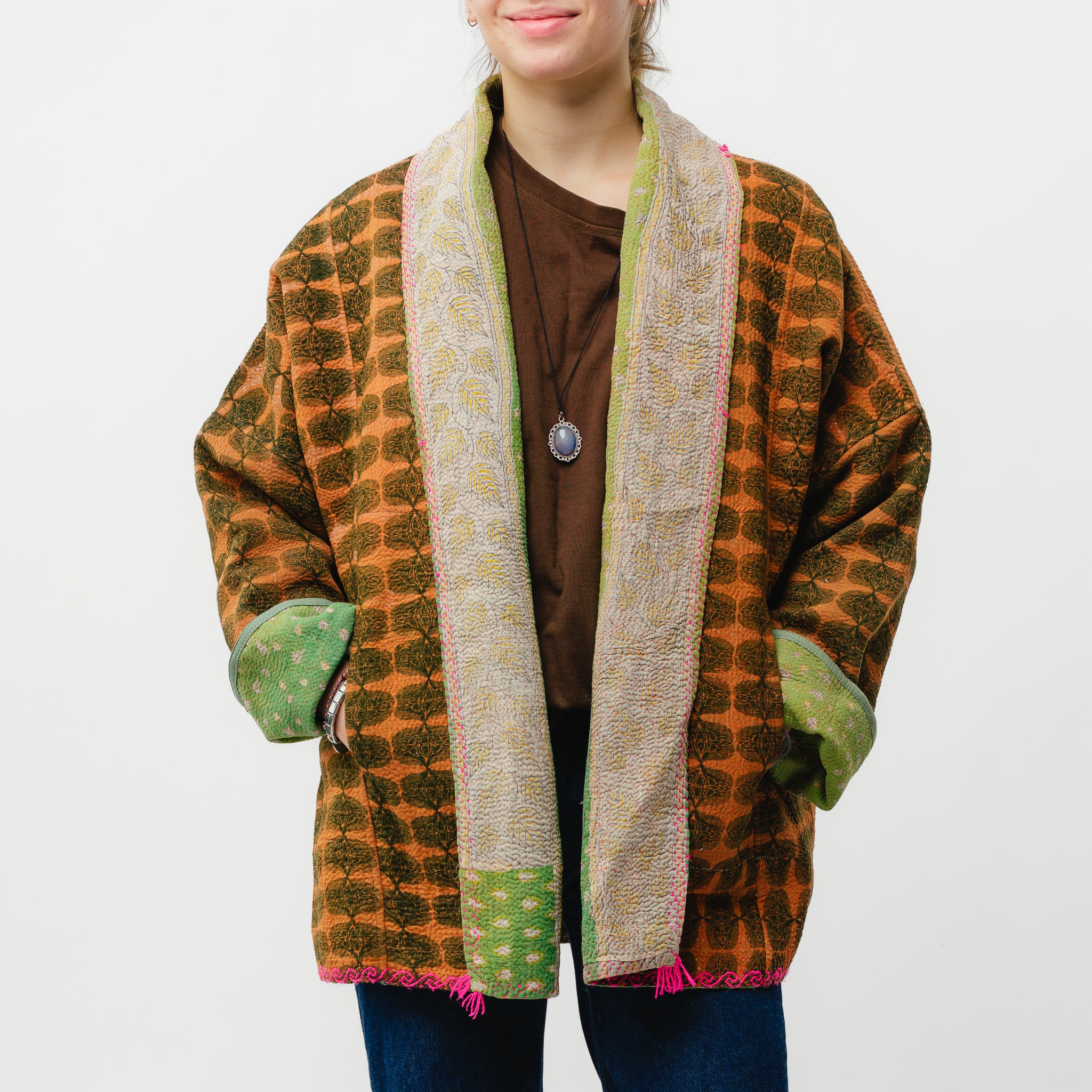 Person wearing a patterned cardigan with green accents on a white background