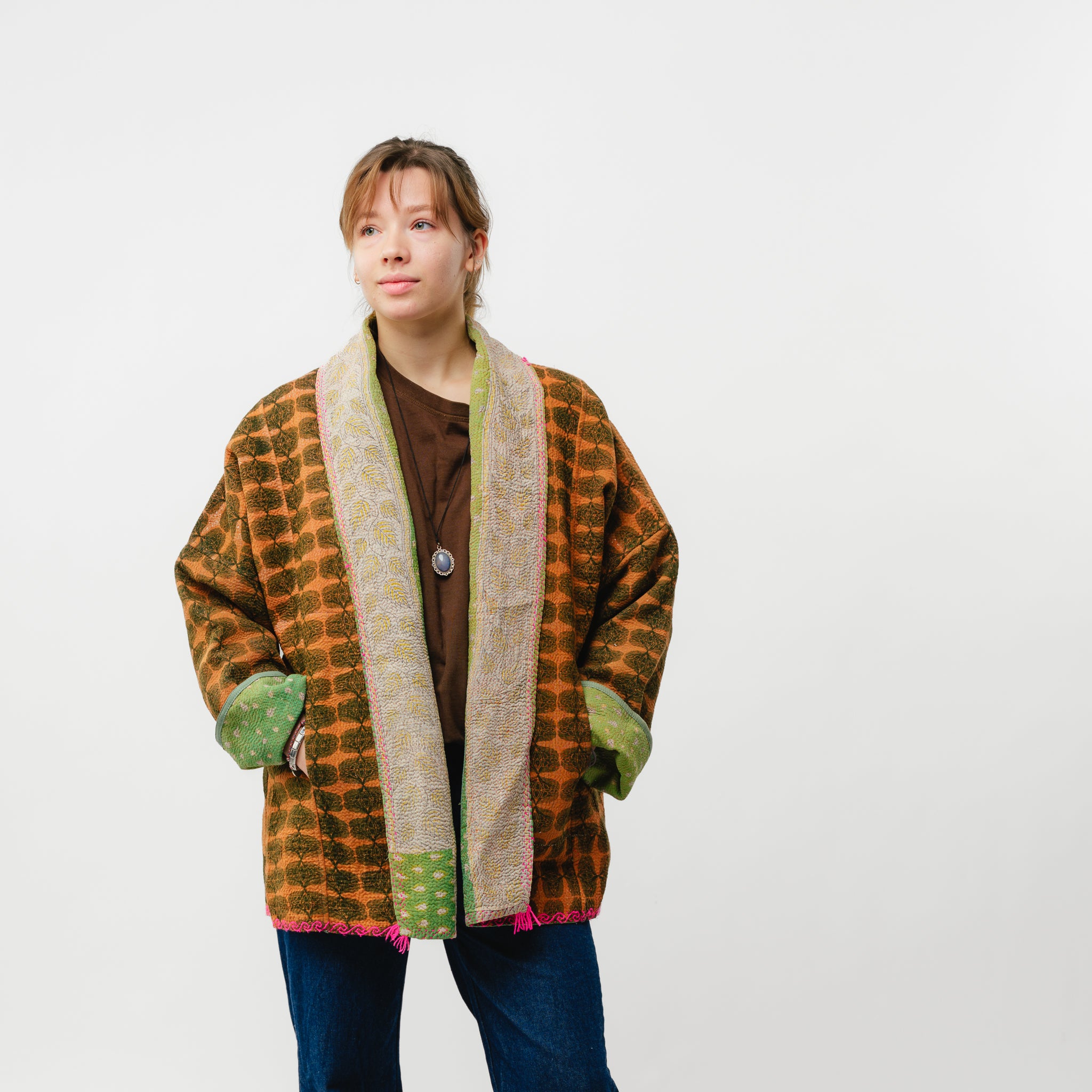Person wearing a patterned jacket with green accents on a white background