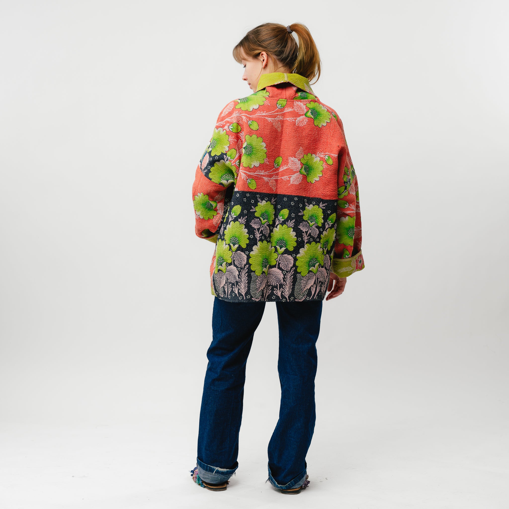 Person wearing a colorful jacket with floral patterns on a white background