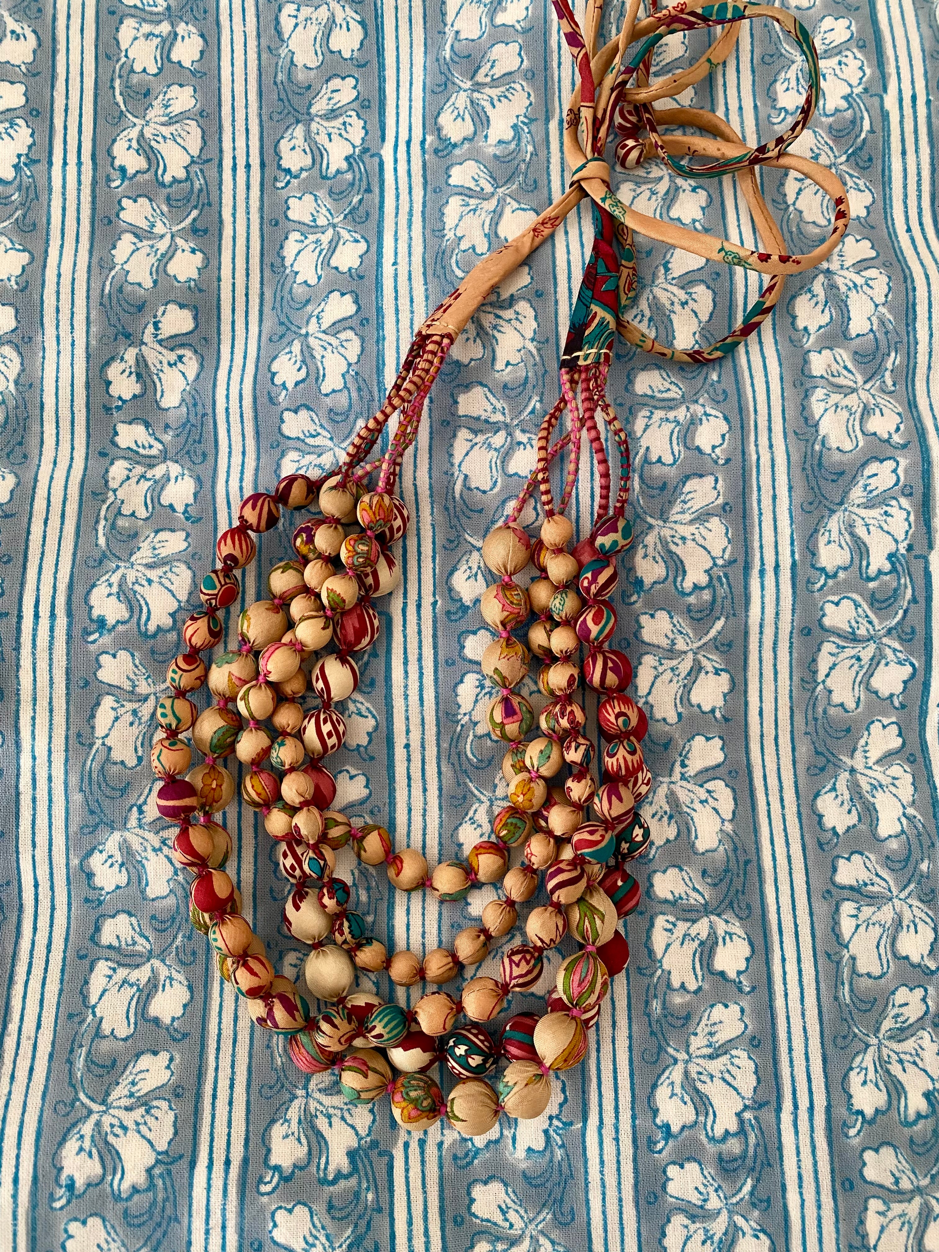Multistrand beaded necklace on a blue and white patterned fabric background