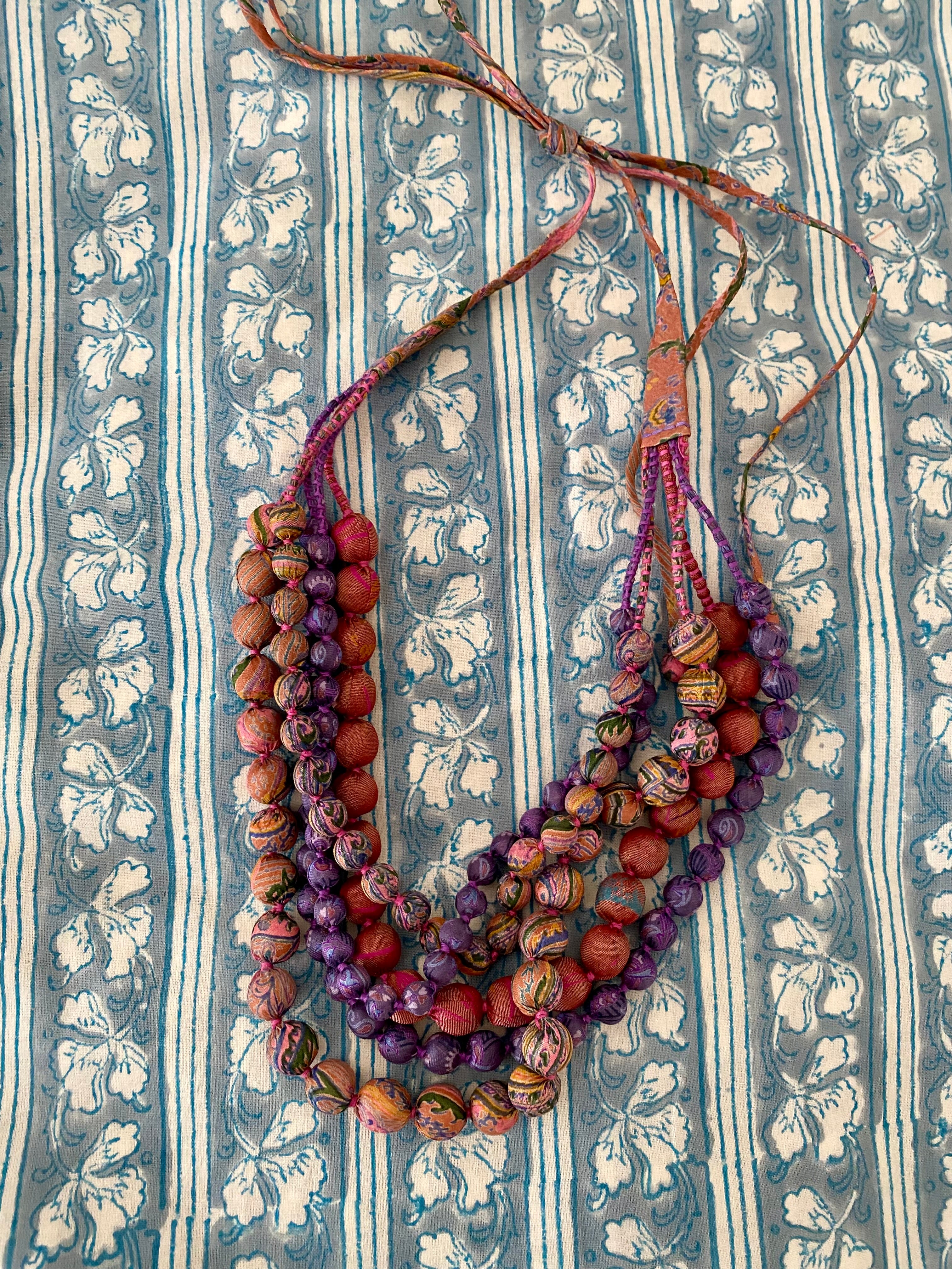 Multicolored beaded necklace on a textured fabric background