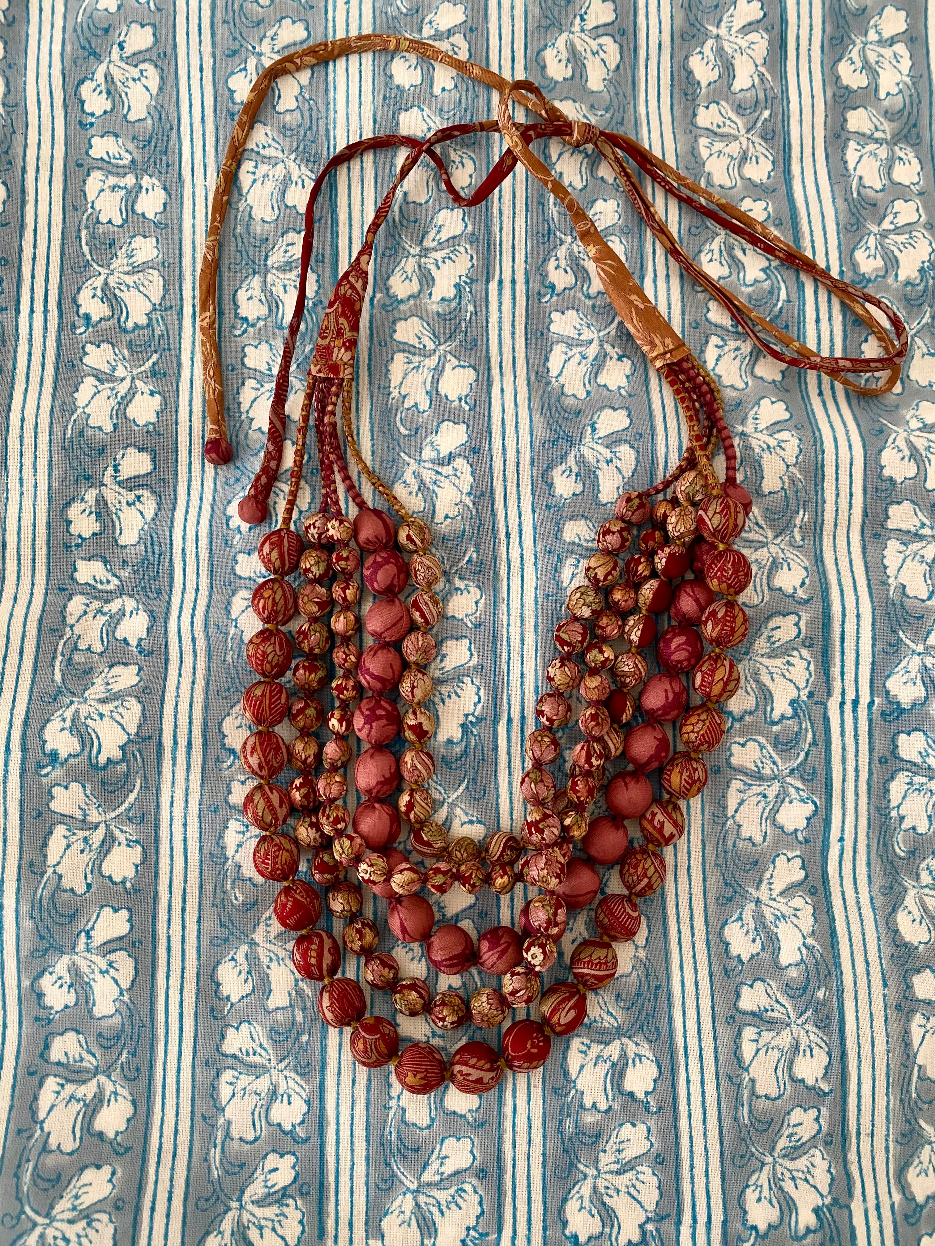 Multistrand beaded necklace on a textured fabric background