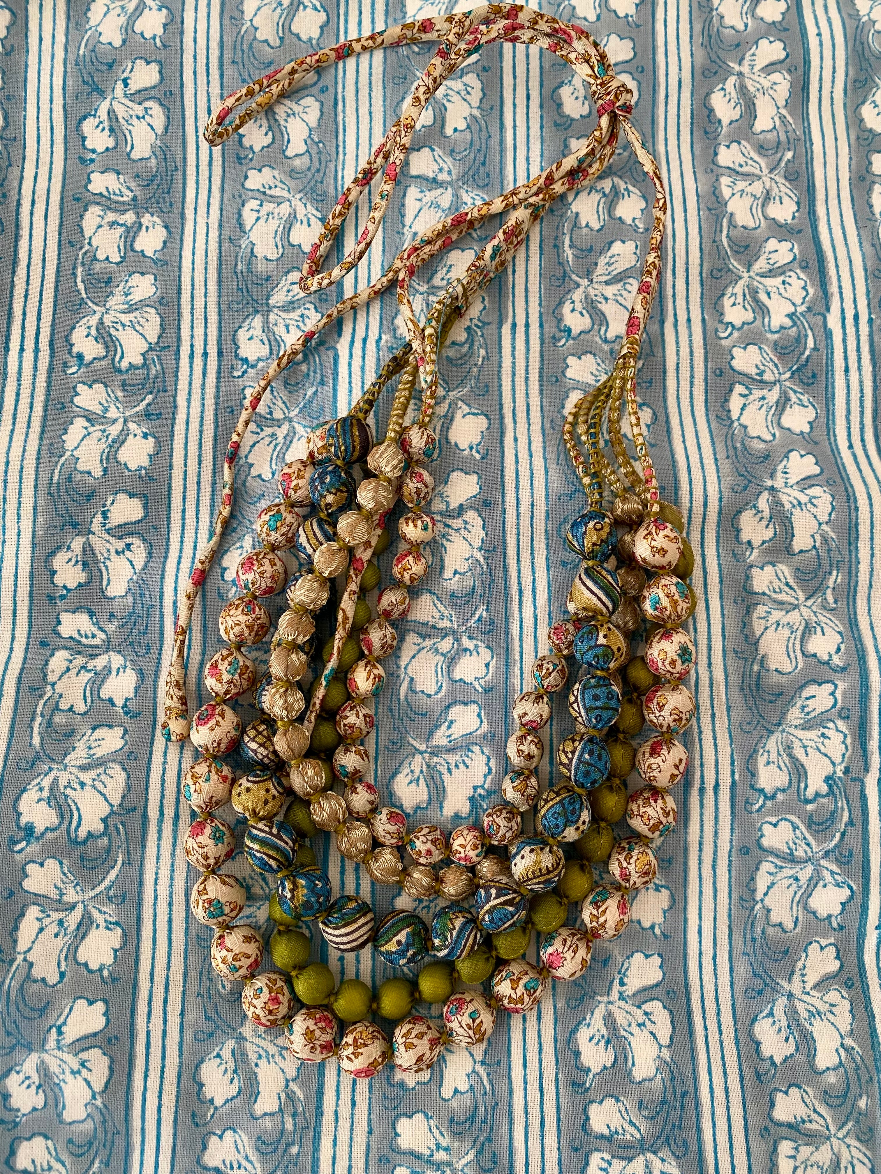 Multistrand beaded necklace on a patterned fabric background