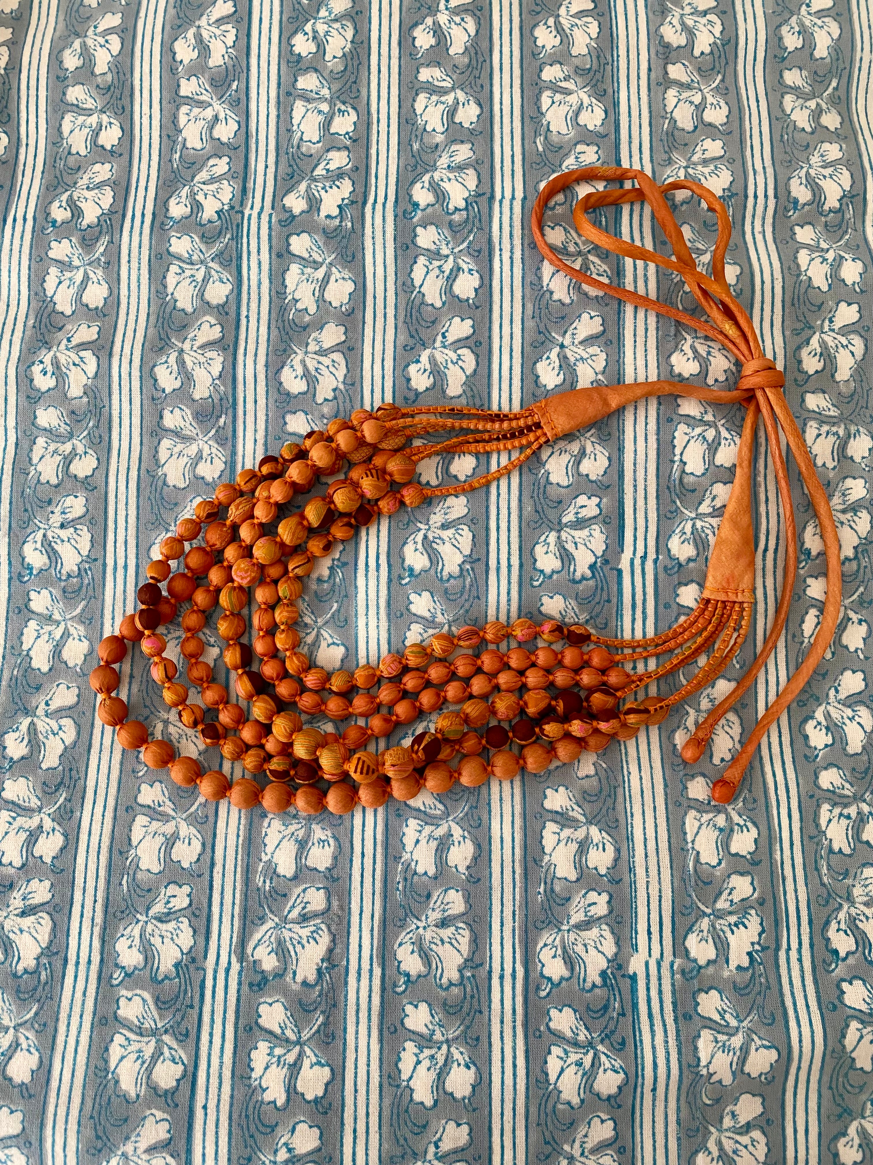 Brown beaded necklace on a blue and white striped fabric background