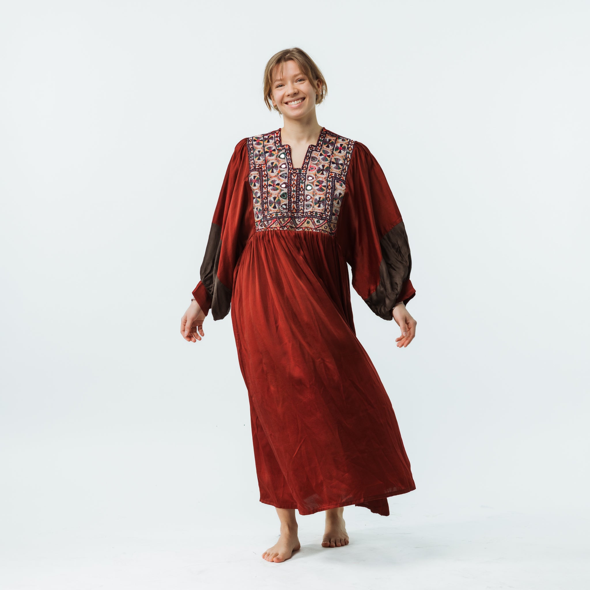 Woman wearing a long red dress with intricate patterns on a white background
