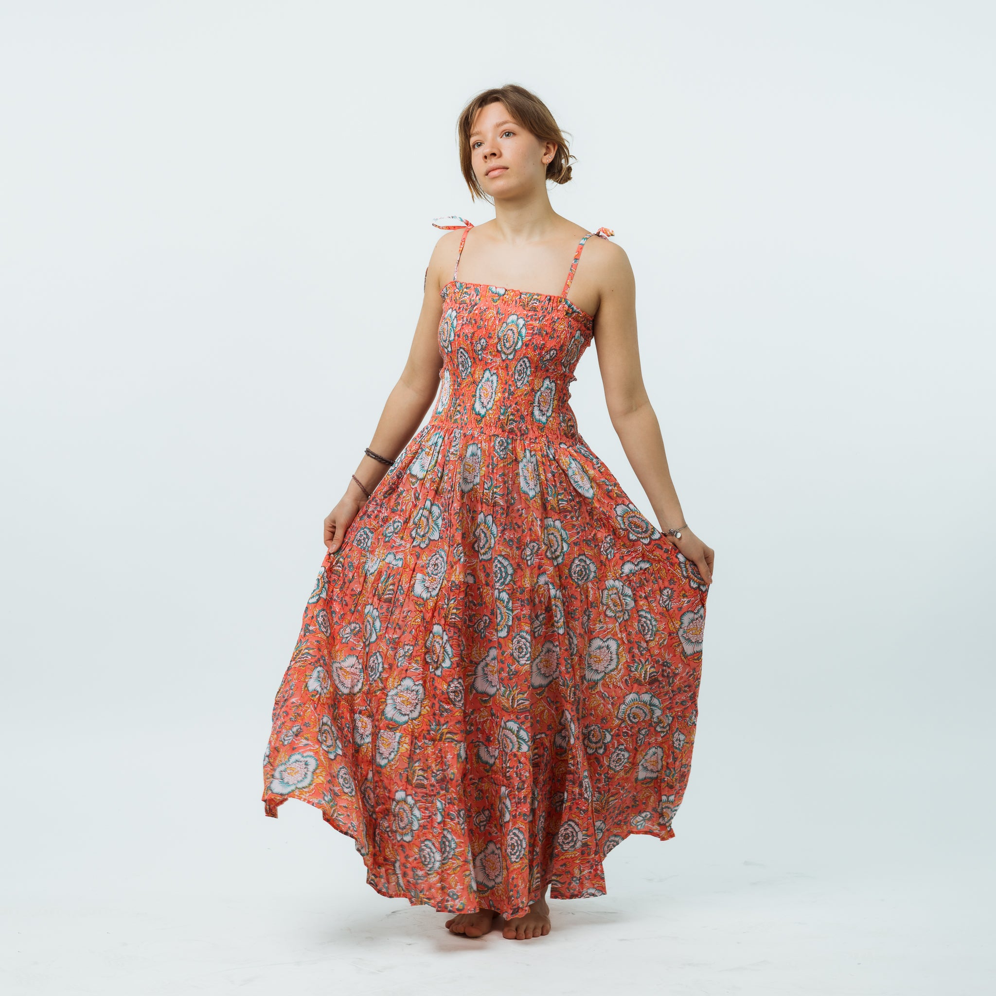 Woman wearing a long orange floral dress on a white background