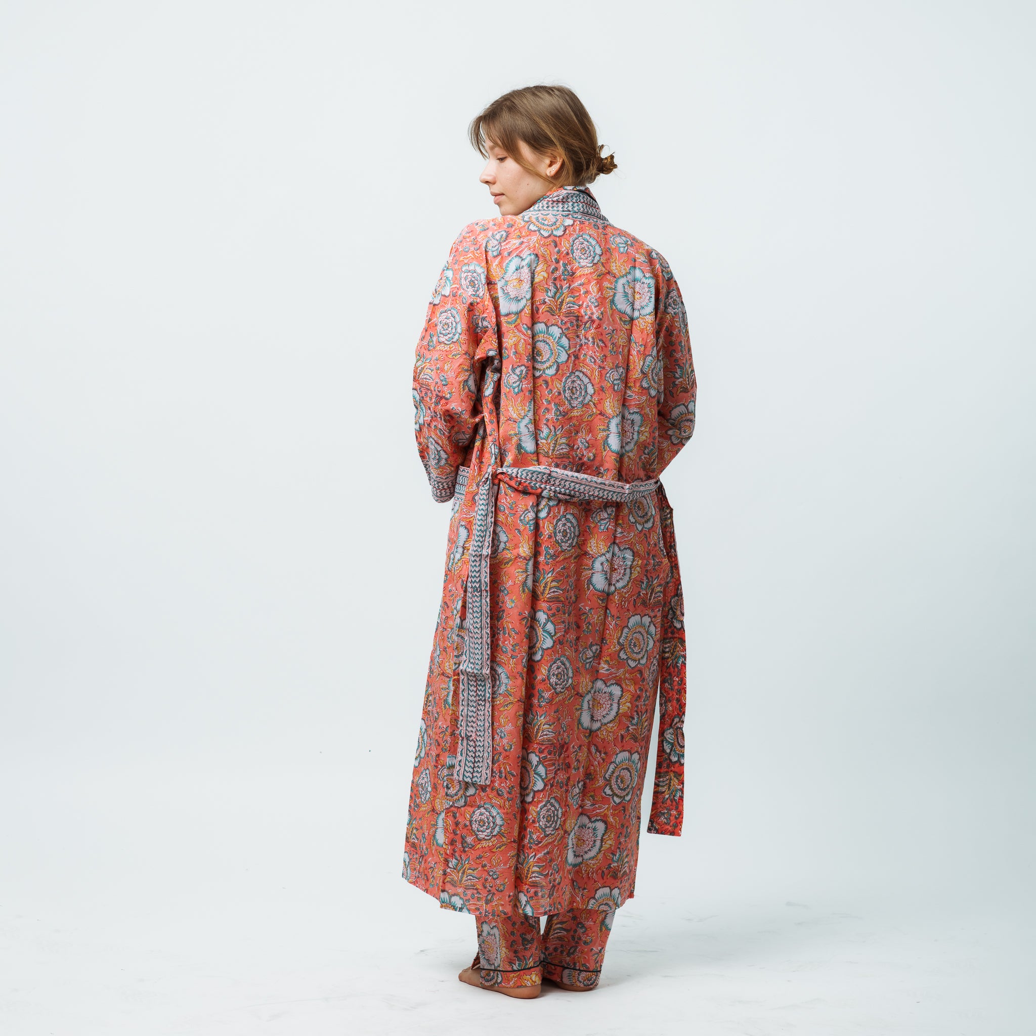 Woman wearing a patterned orange and gray robe on a white background