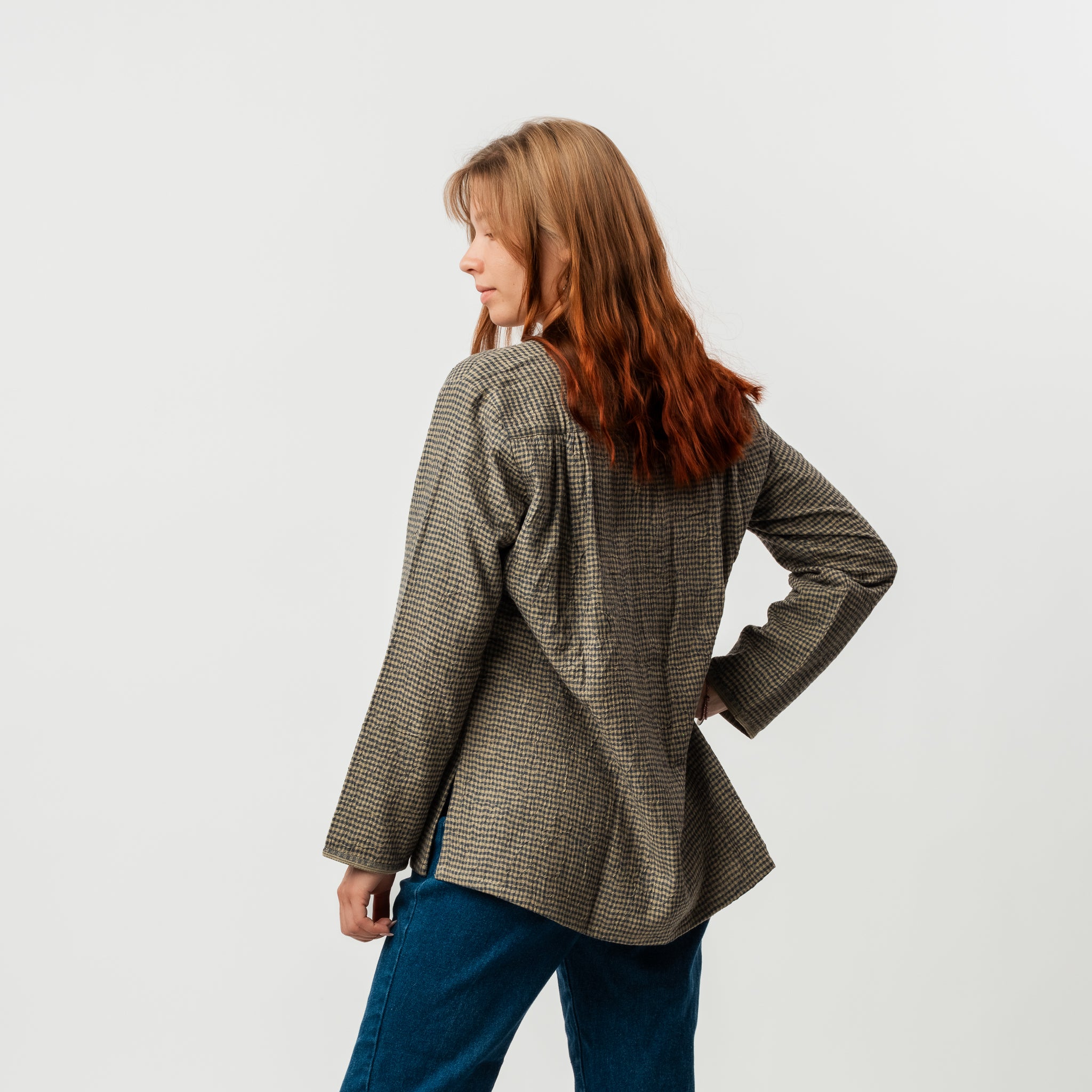 Woman wearing a checkered blazer and blue pants on a white background