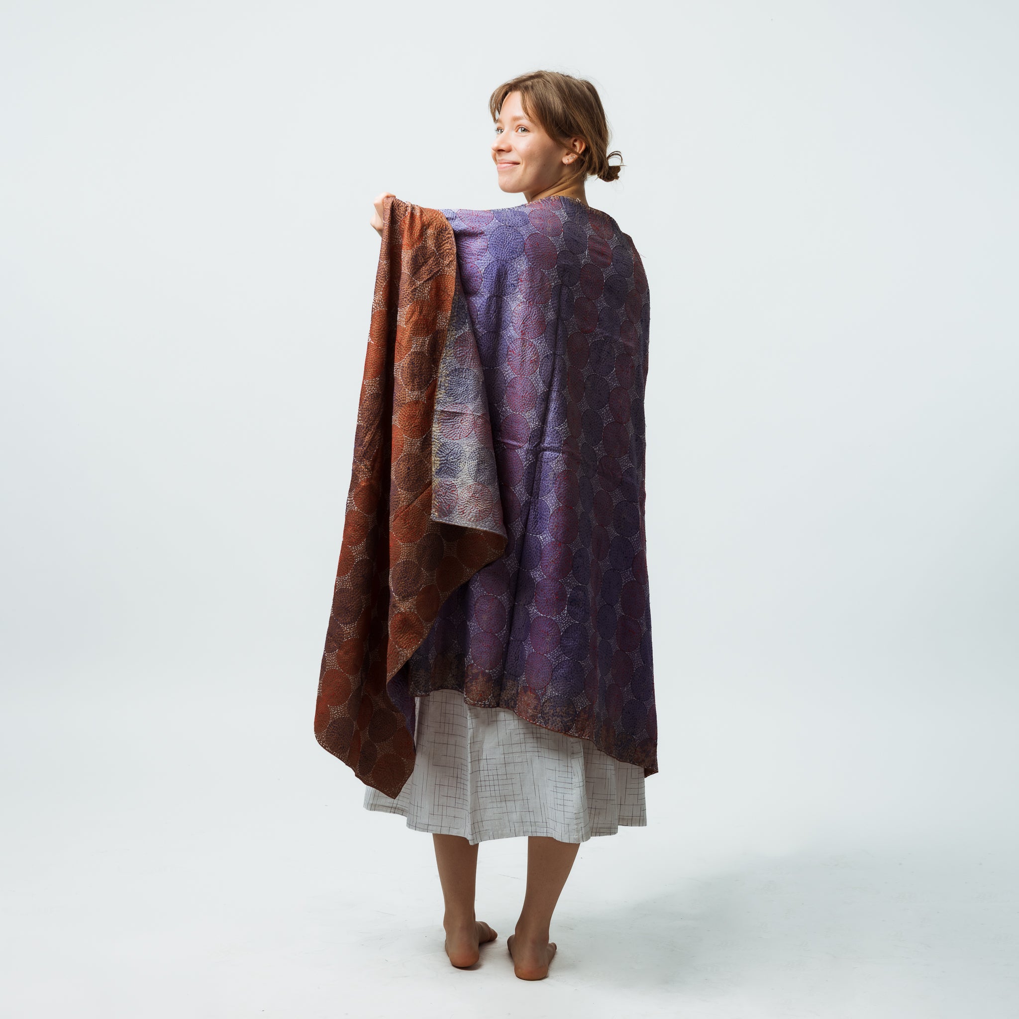 Woman wearing a patterned shawl over a plain garment on a white background