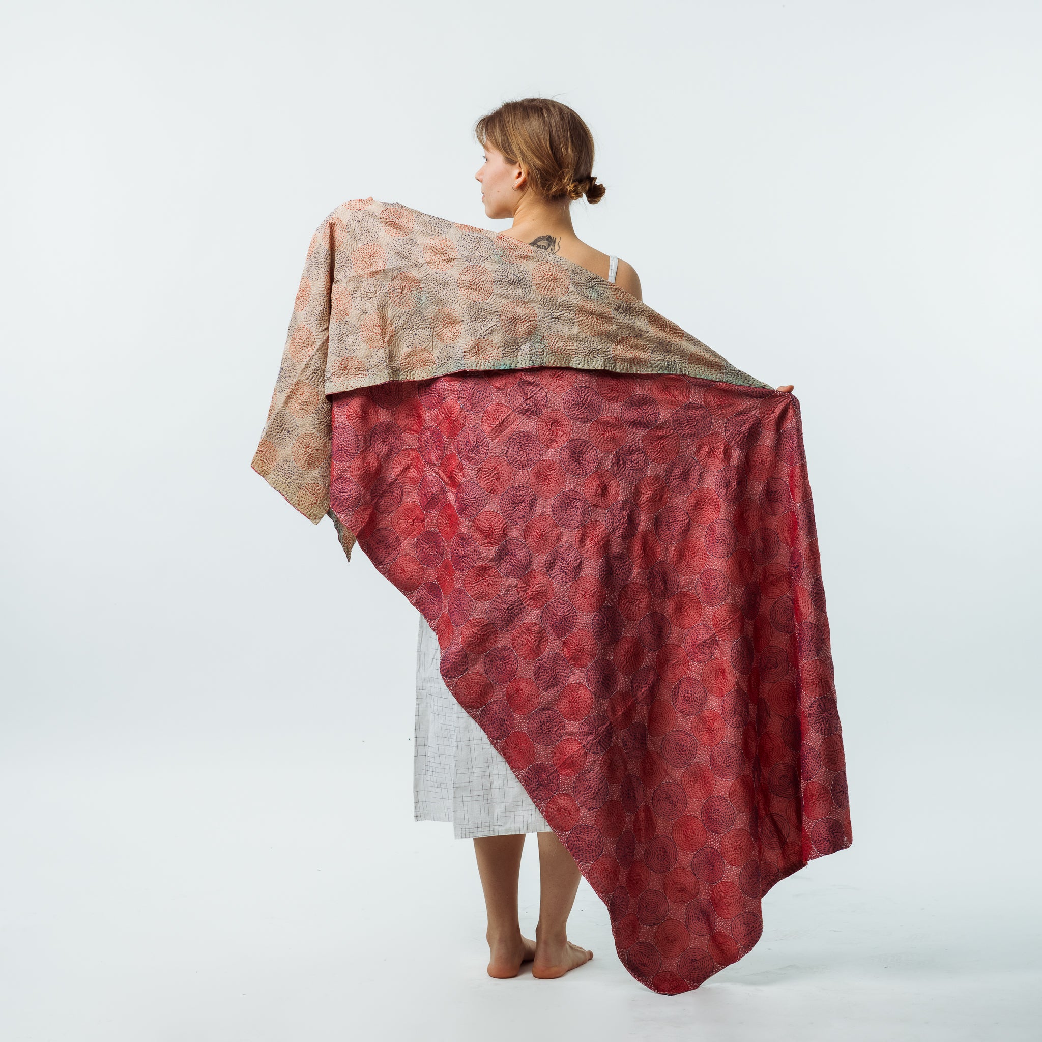 Woman holding a patterned fabric over her shoulders against a white background