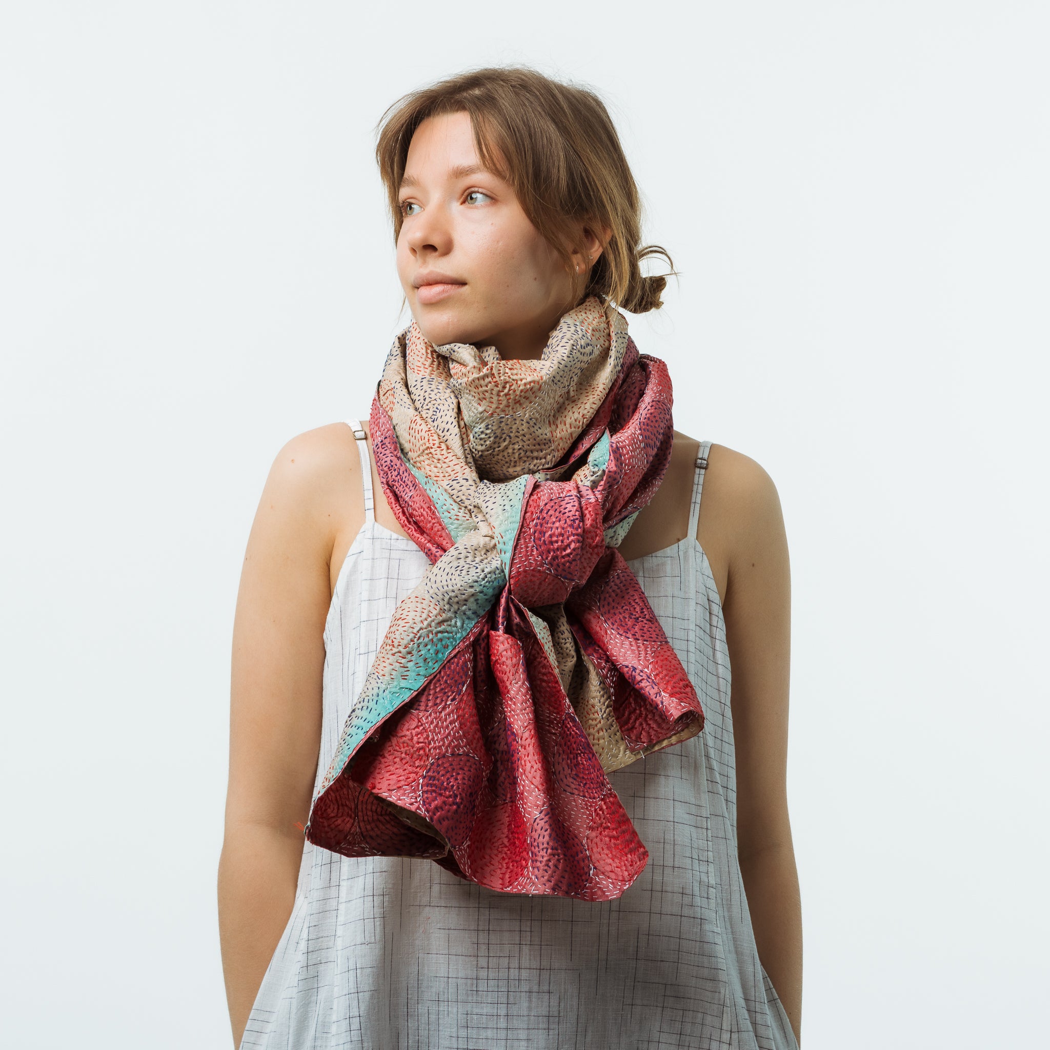 Woman wearing a colorful scarf on a plain background