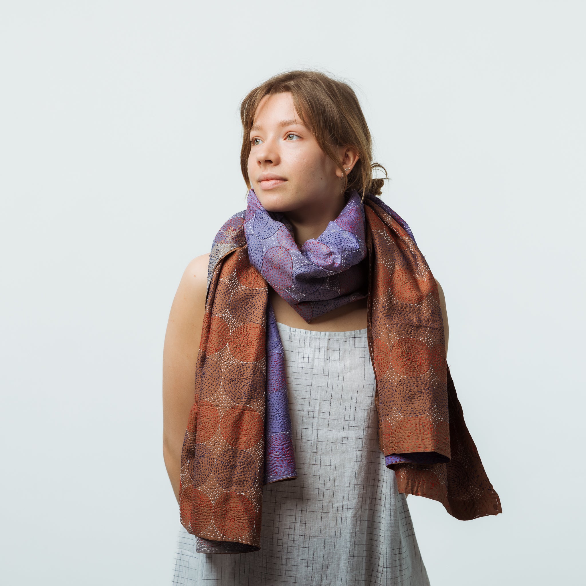 Woman wearing a patterned scarf on a plain background
