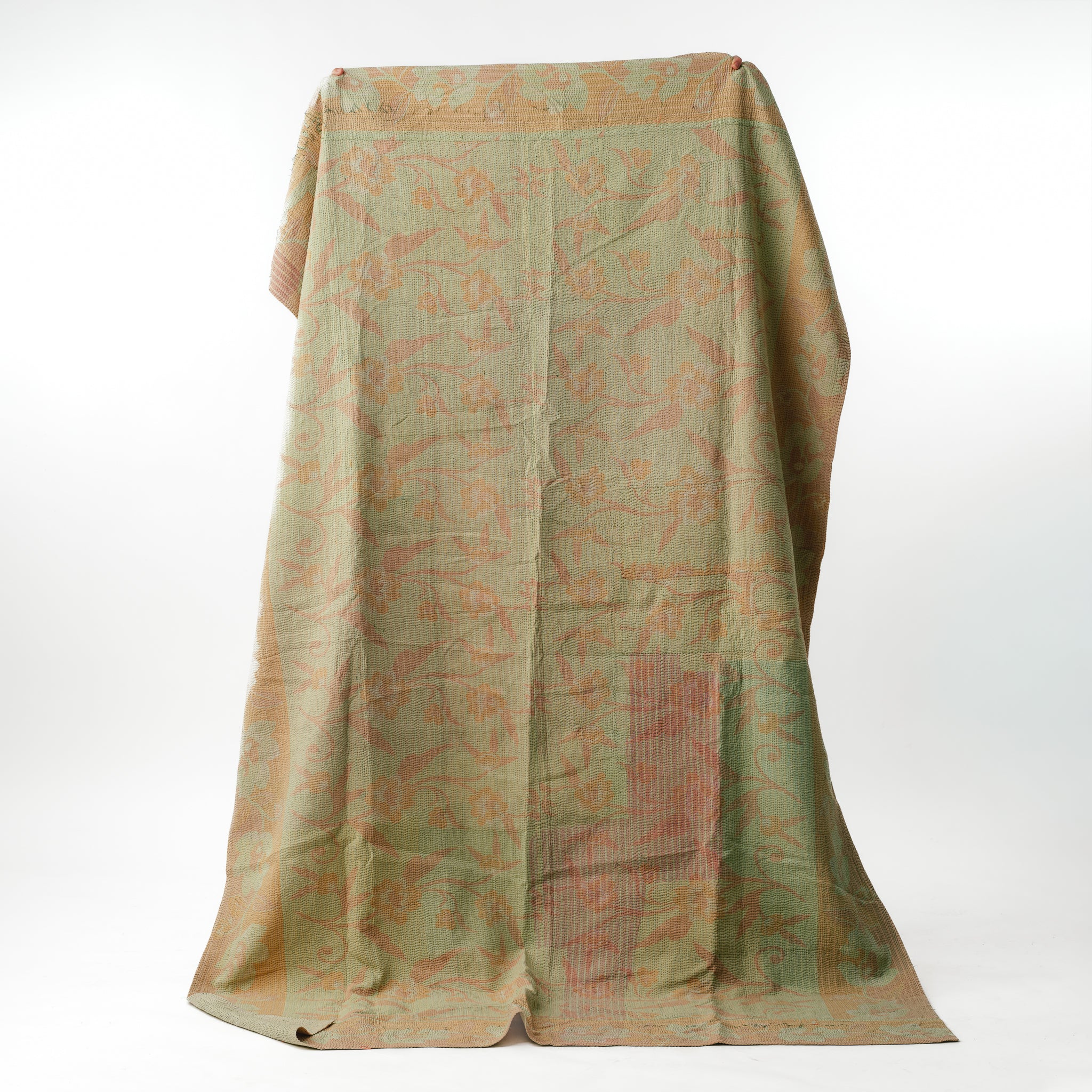 Green and orange patterned fabric draped over a white background