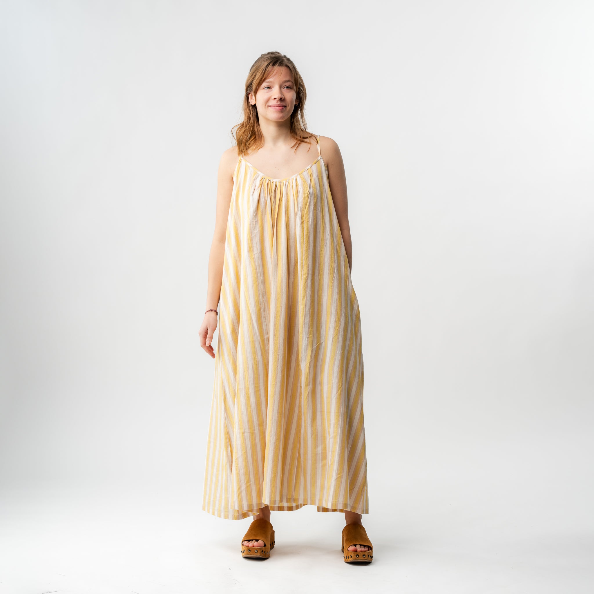 Woman wearing a yellow striped dress on a white background