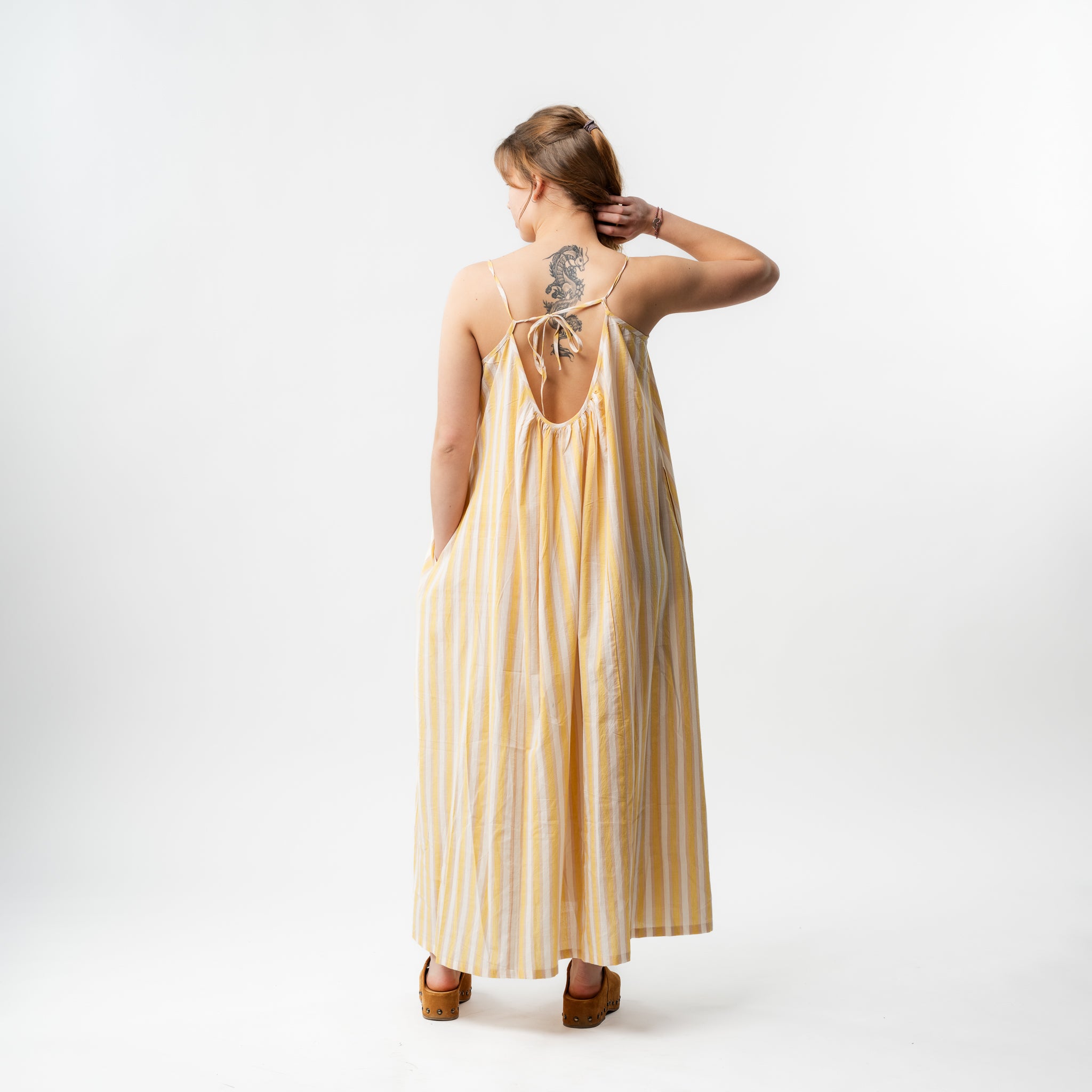 Woman wearing a yellow and white striped dress on a white background