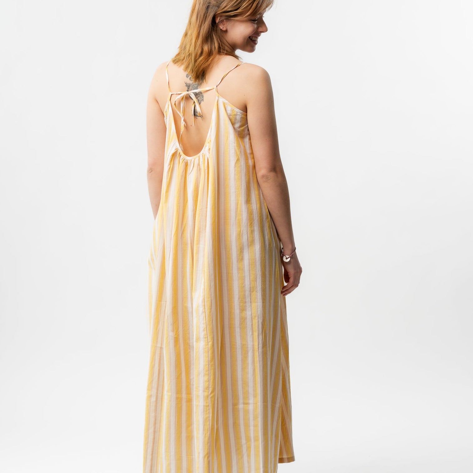 Woman wearing a yellow and white striped dress on a white background