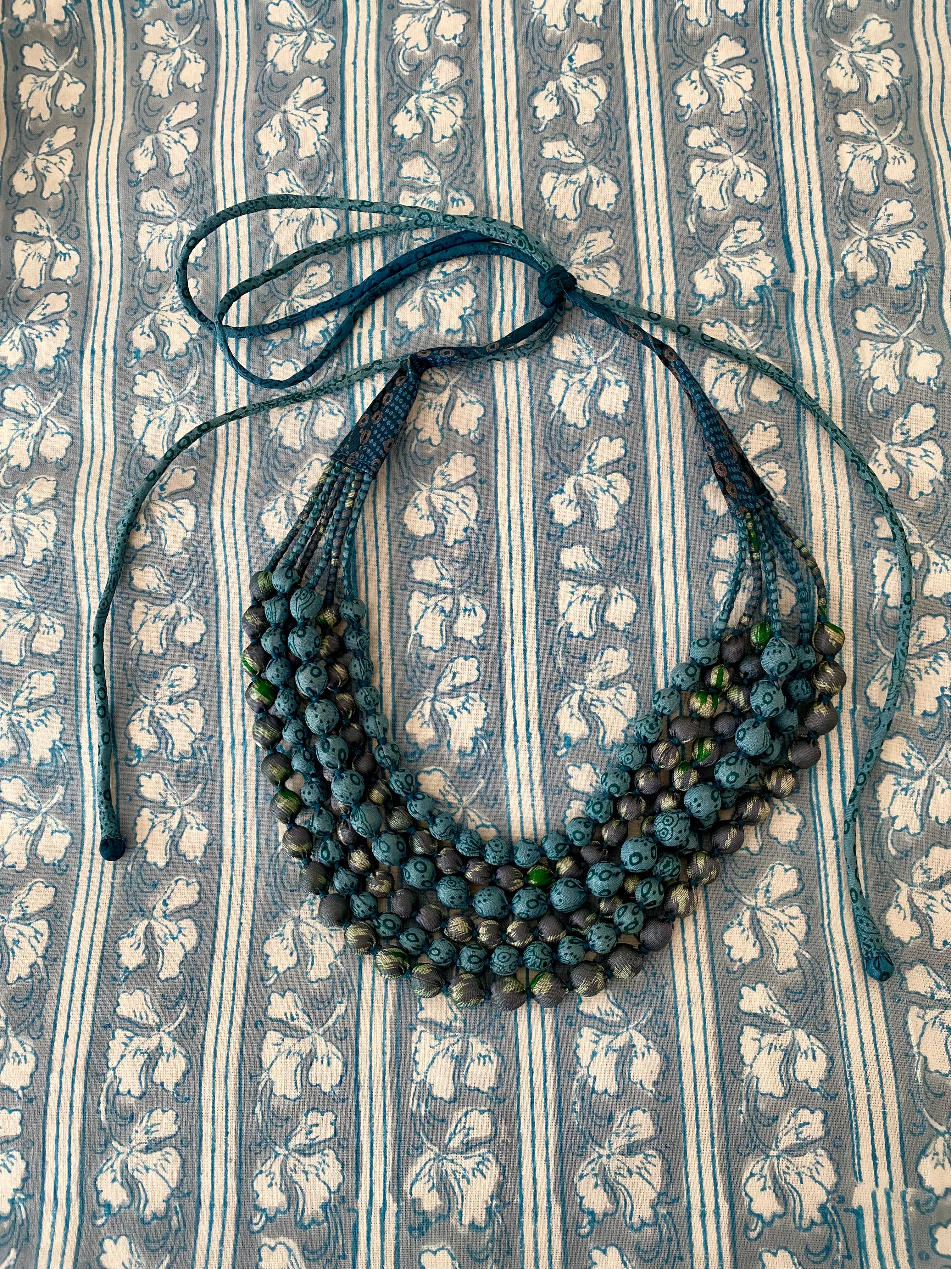 Necklace with green beads on a patterned fabric background