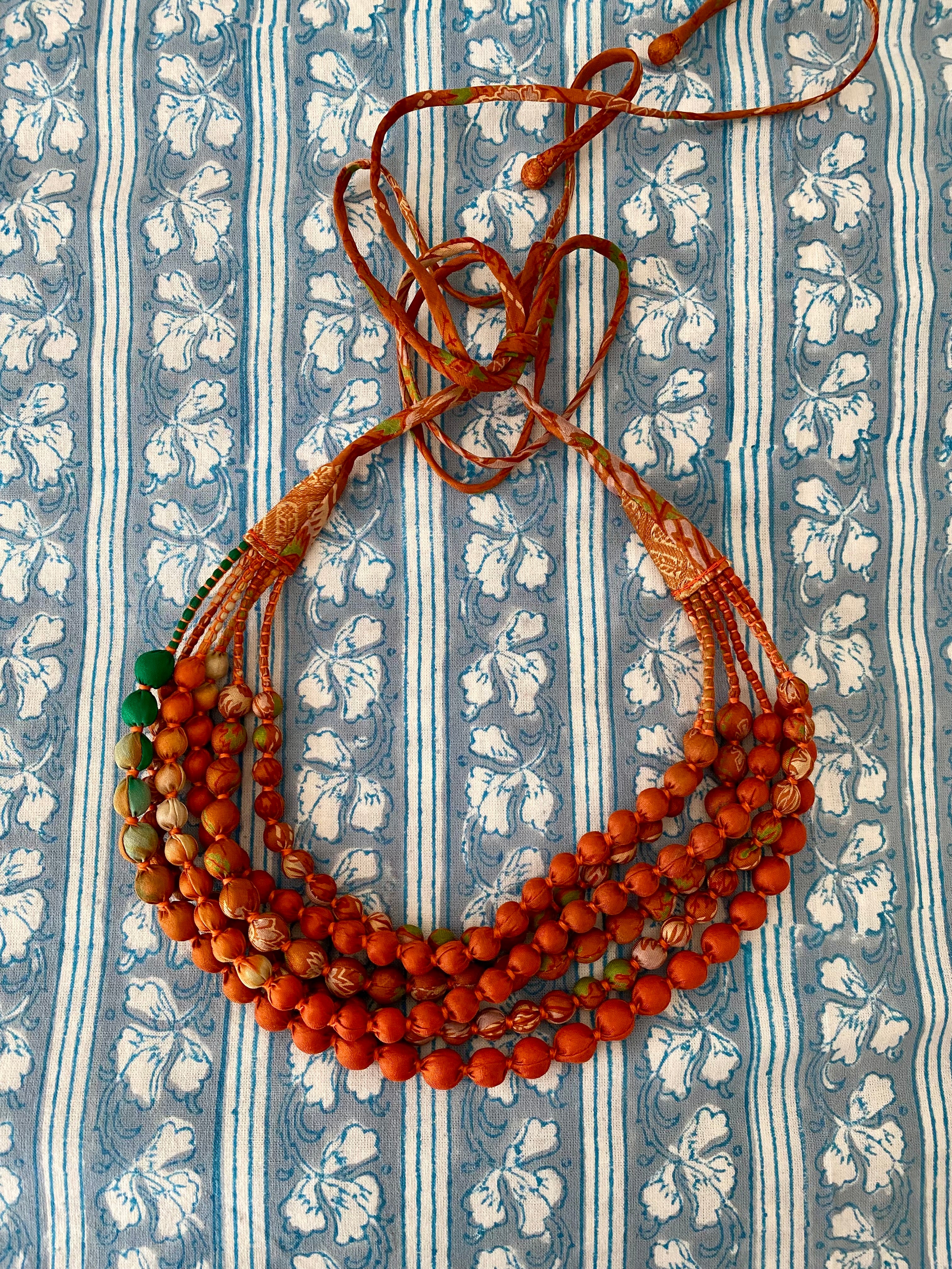 Beaded necklace on a blue and white patterned fabric background