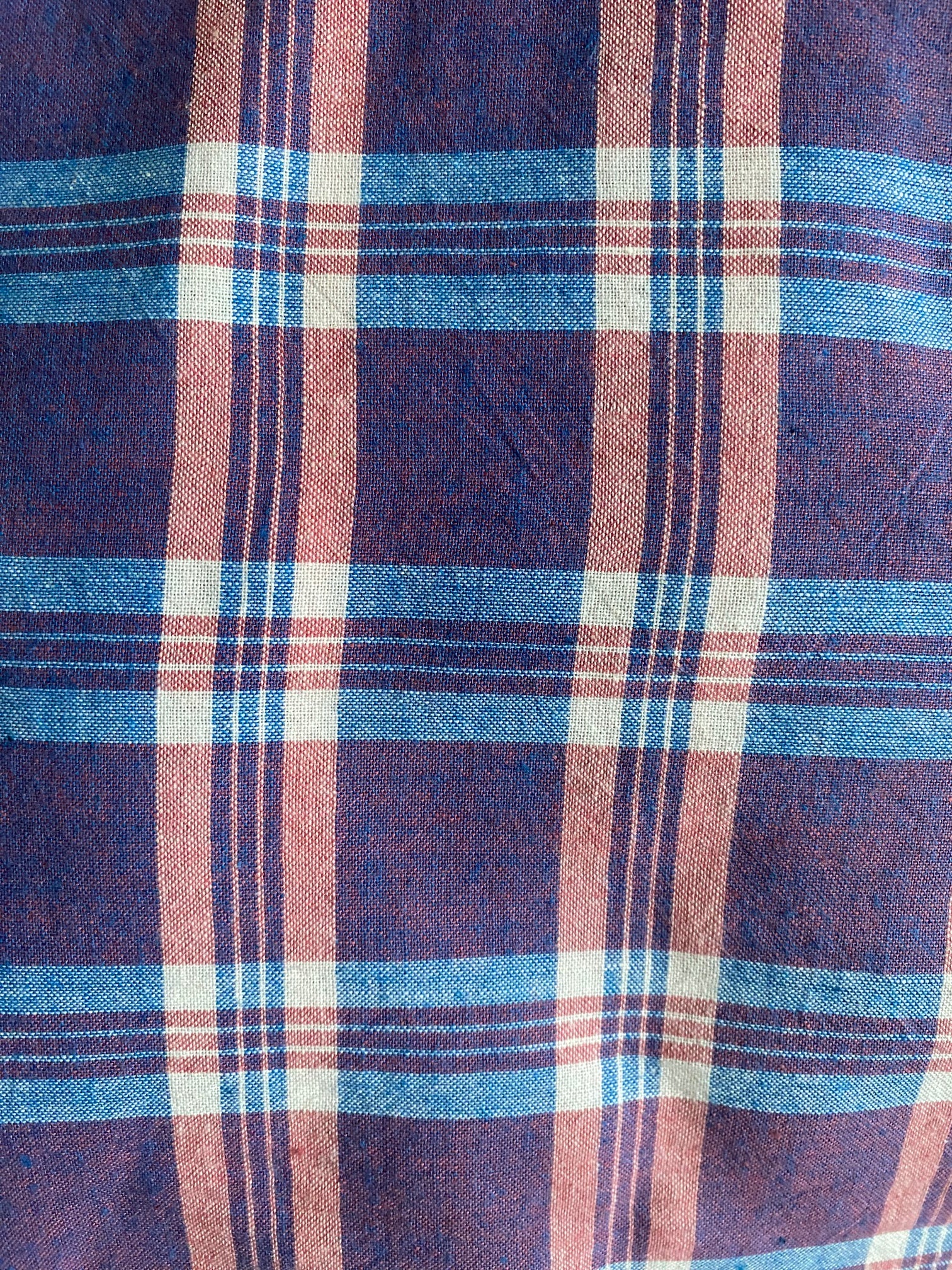 Close-up of a plaid fabric with blue, red, and white colors.