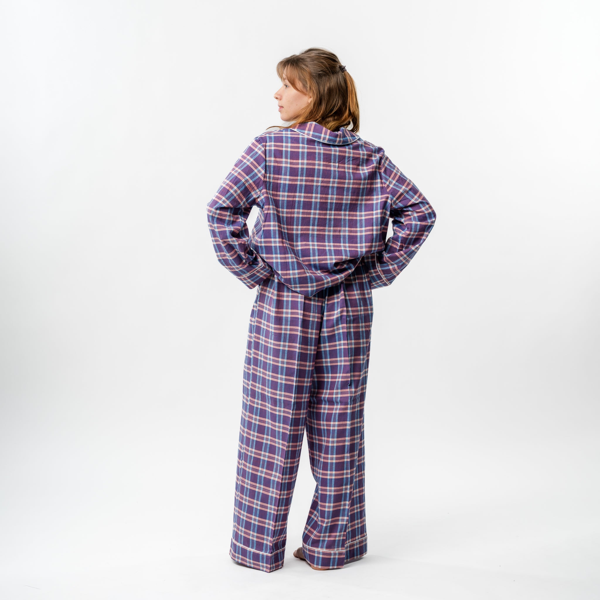 Person wearing a blue and red plaid pajama set on a white background