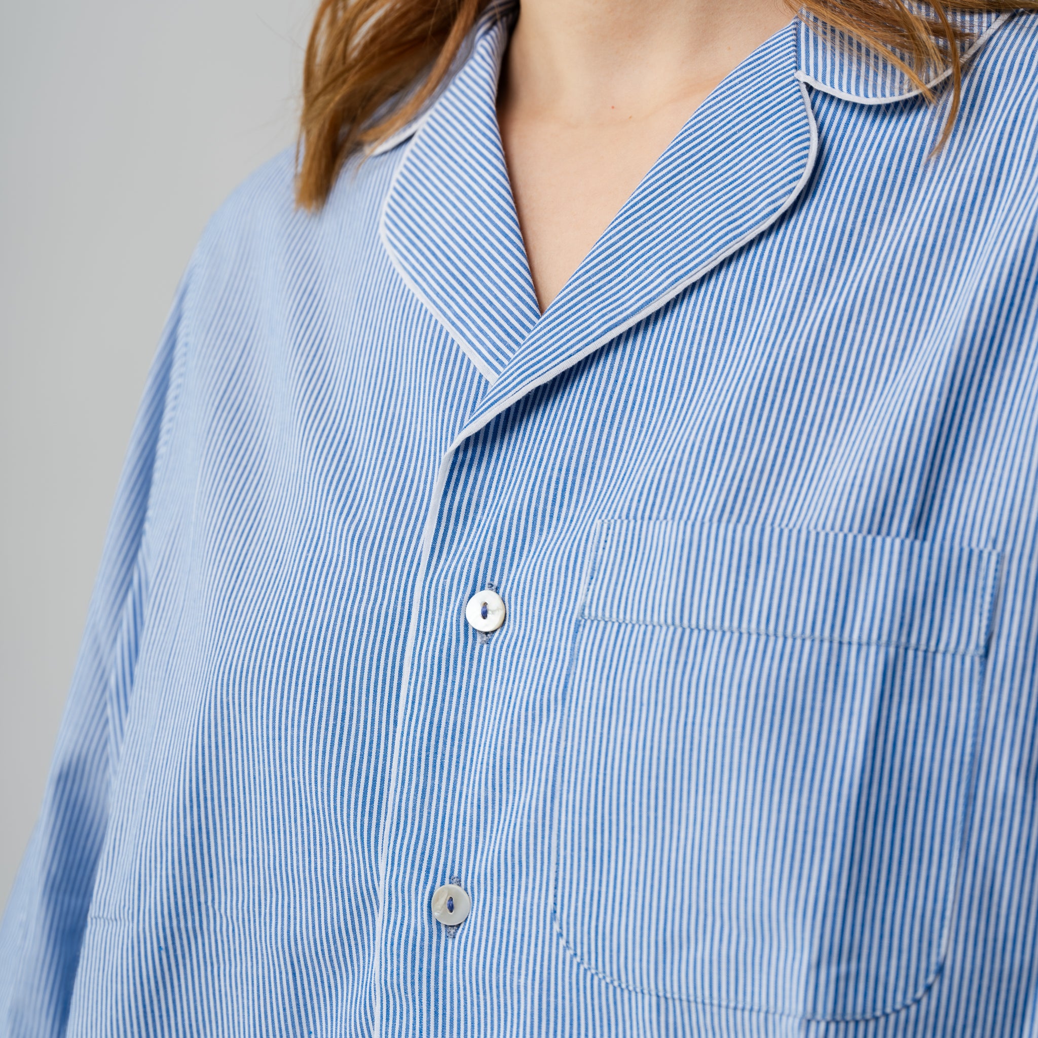 Close-up of a blue and white striped shirt with a collar on a gray background