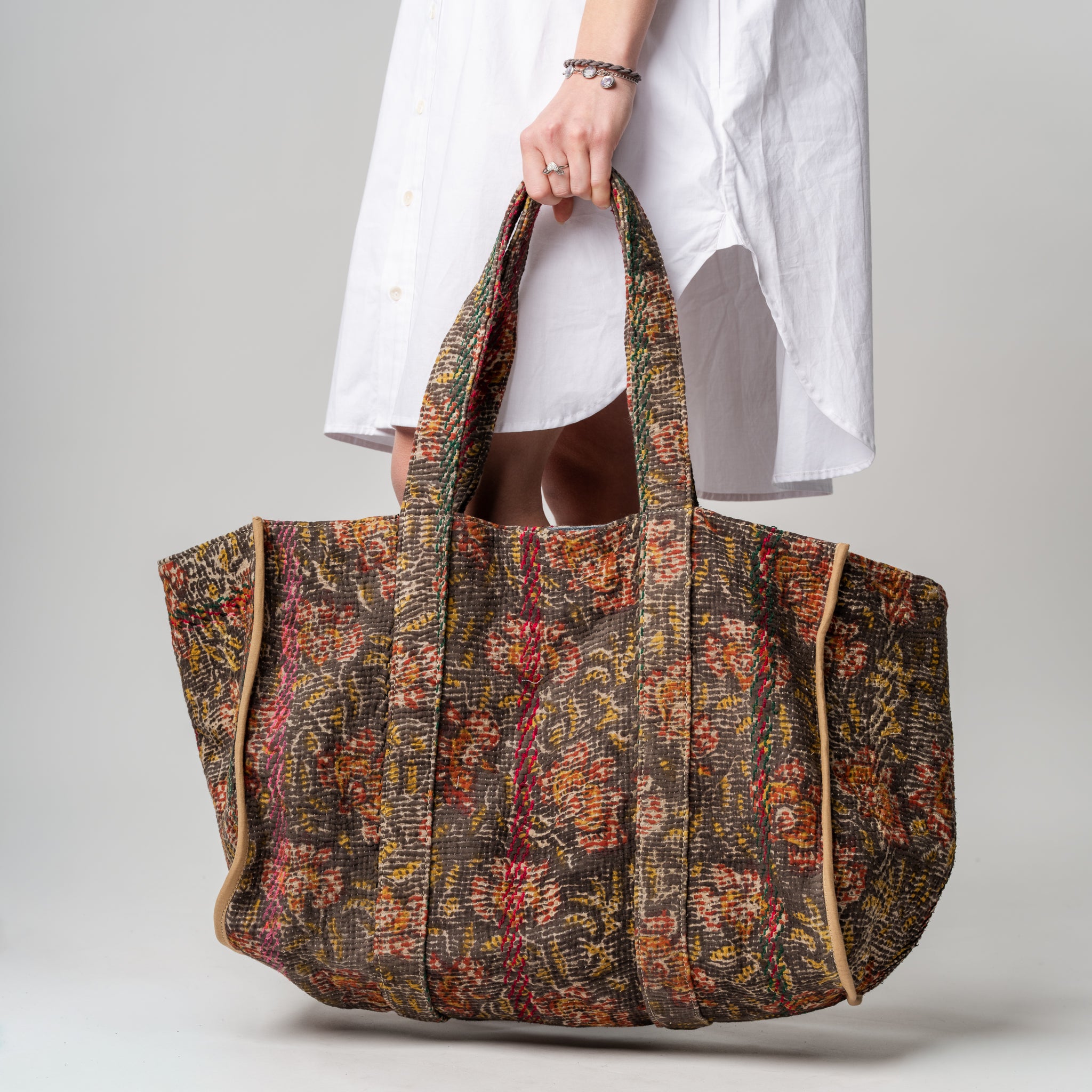 Person holding a patterned tote bag against a plain background