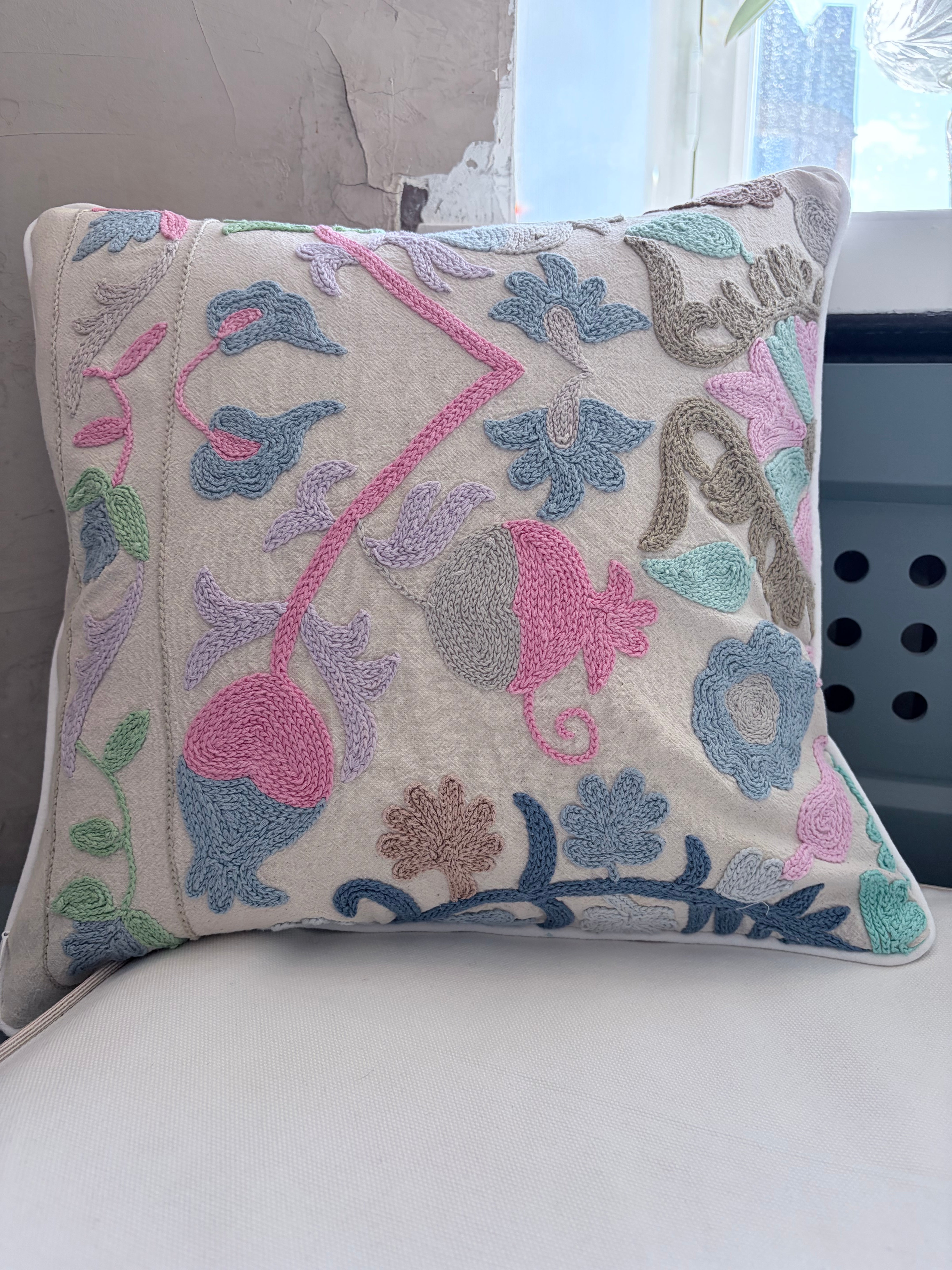 Decorative pillow with floral embroidery on a white surface
