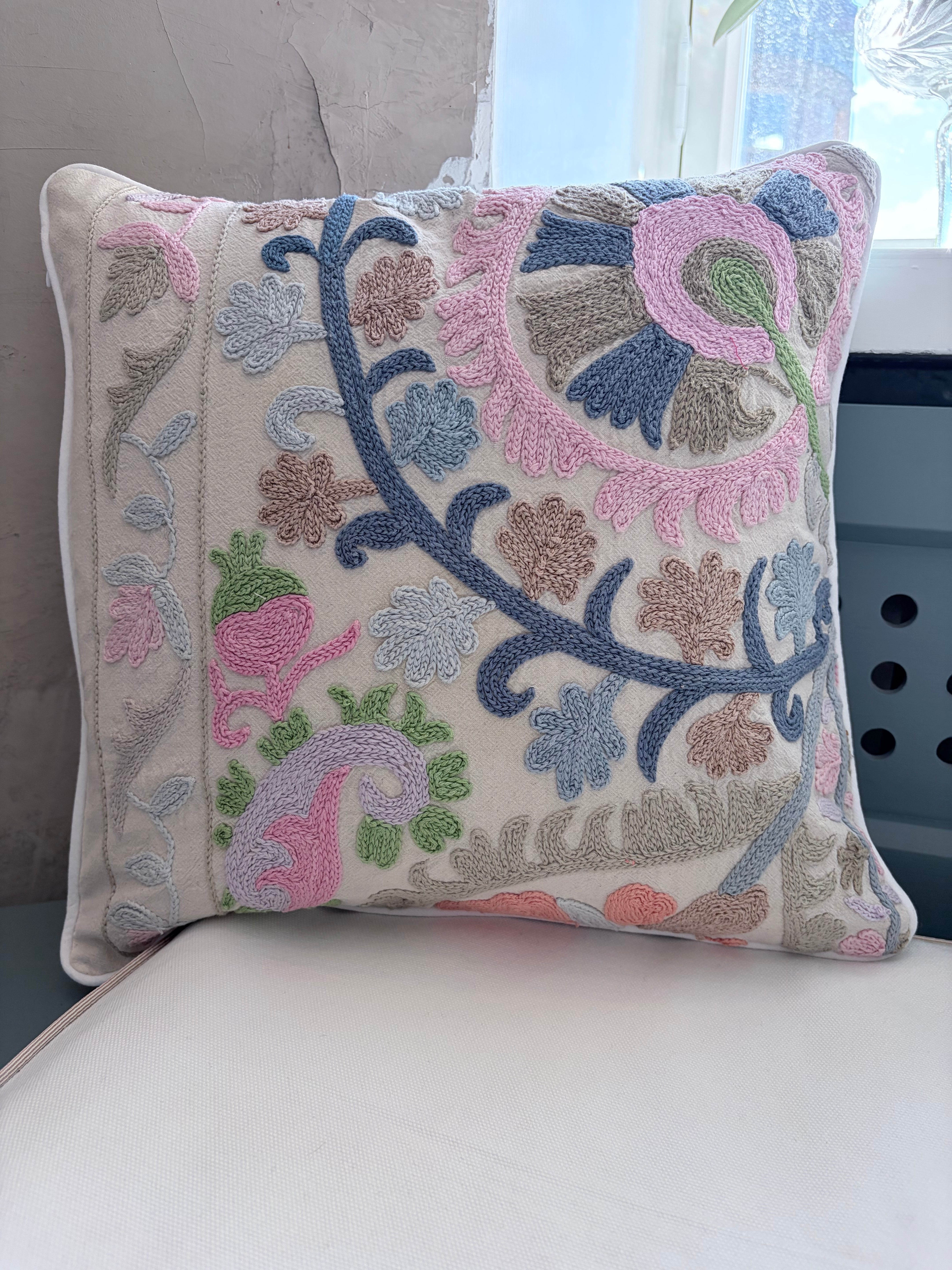 Decorative pillow with floral embroidery on a white surface