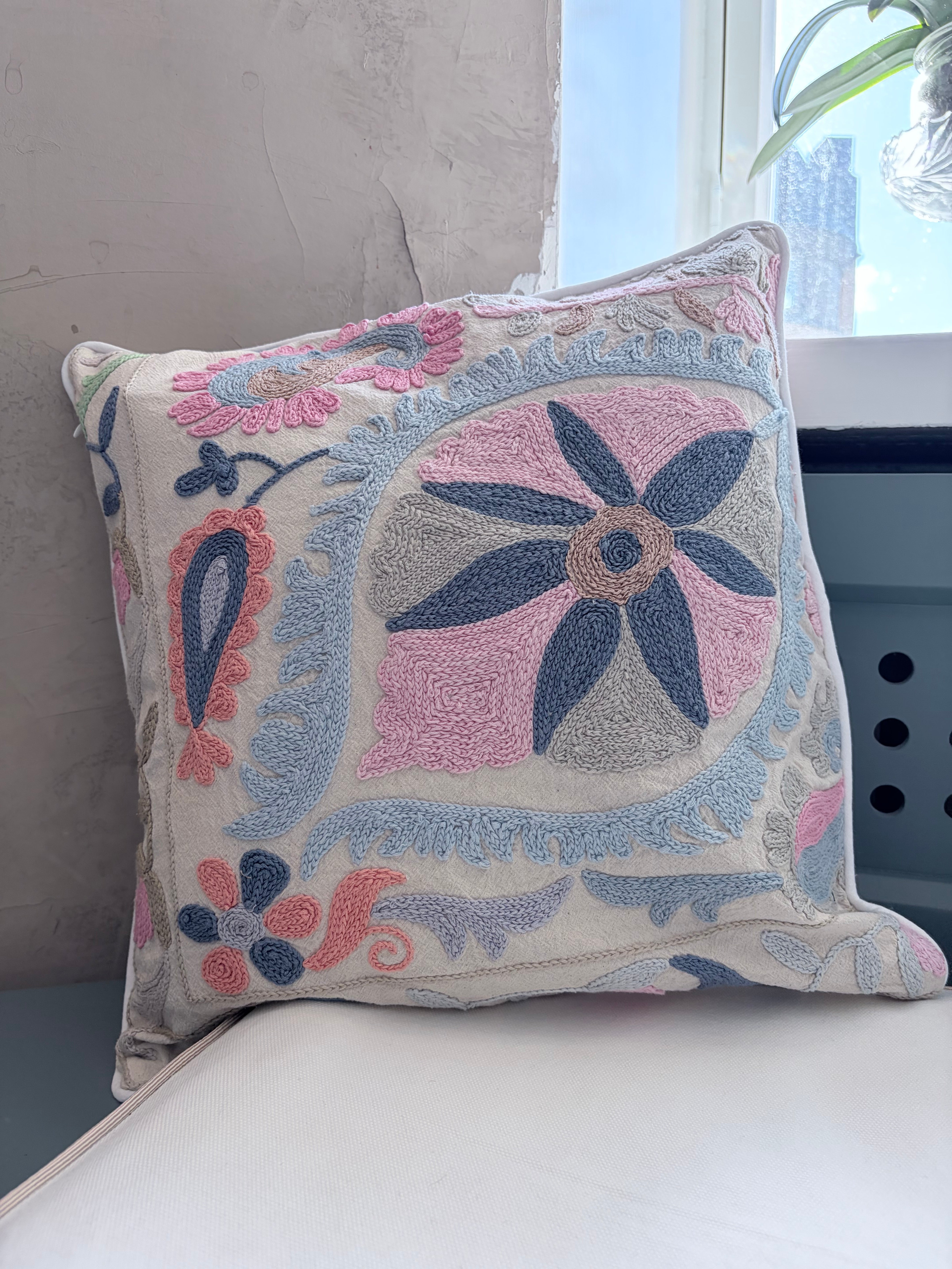 Decorative pillow with floral embroidery on a white surface