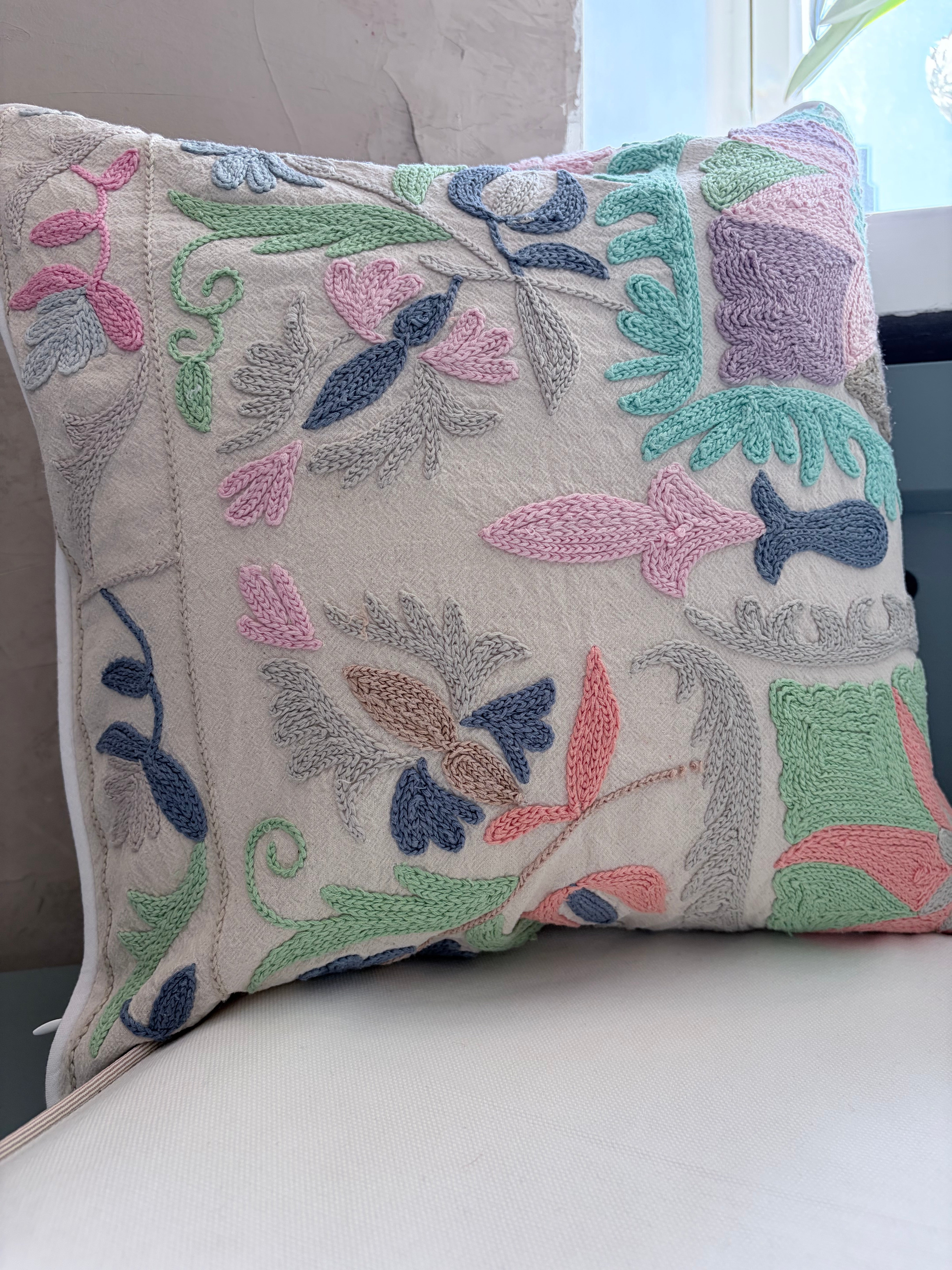 Decorative pillow with floral embroidery on a white surface