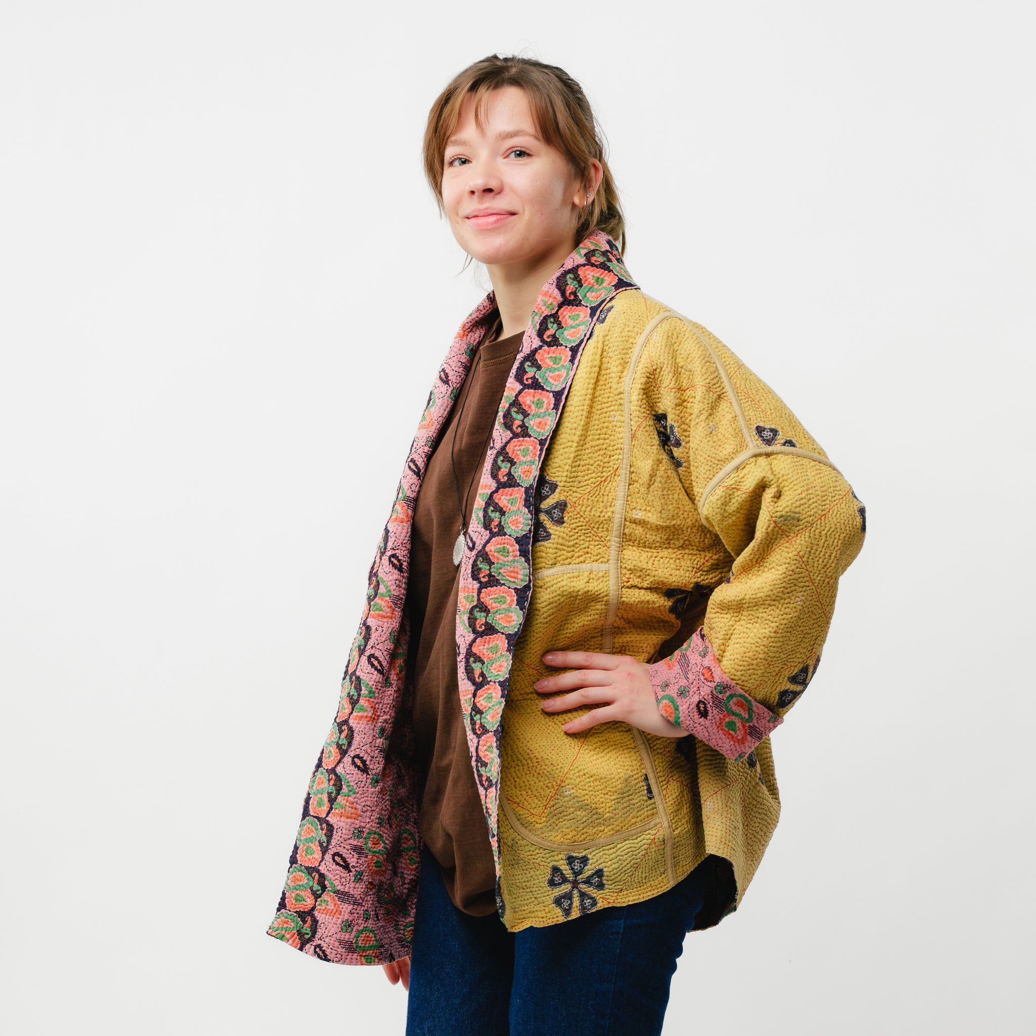 Woman wearing a yellow jacket with floral patterns on a white background