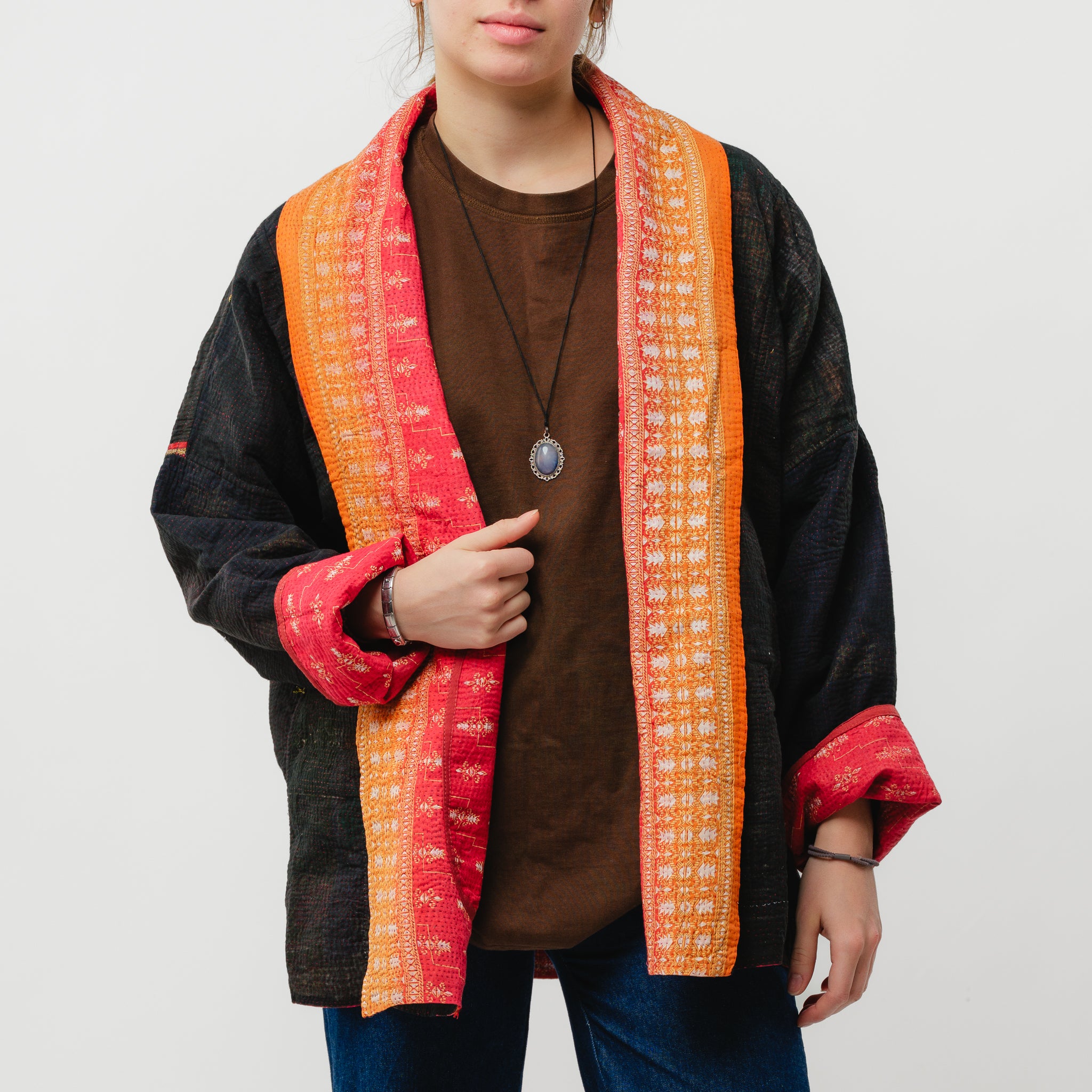 Person wearing a black jacket with an orange and red patterned scarf on a white background