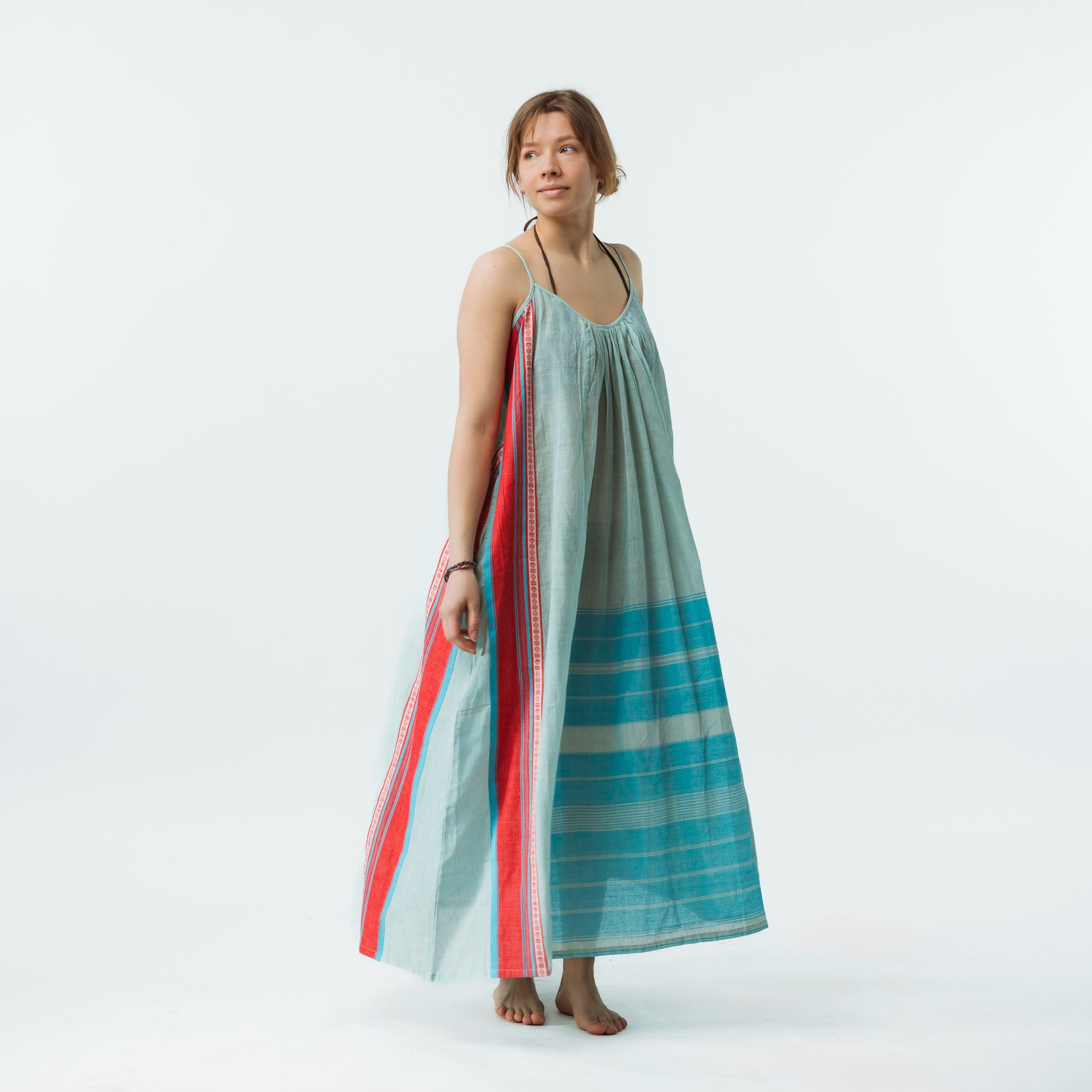 Woman wearing a long, light blue dress with red and green stripes on a white background