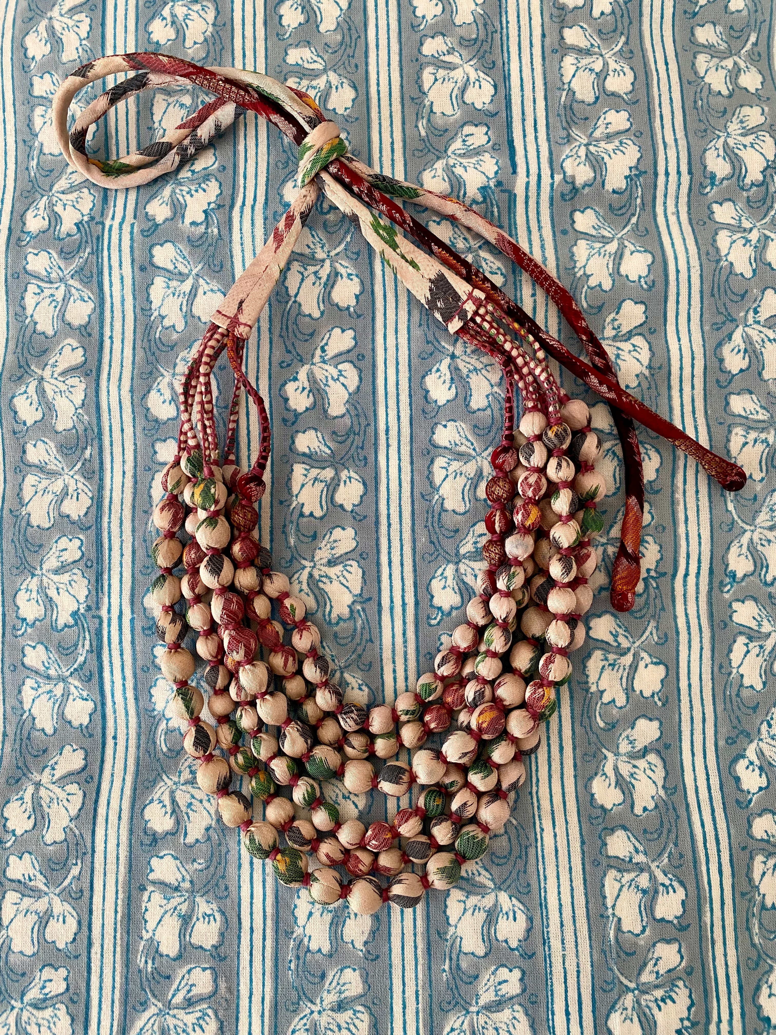 Multistrand beaded necklace on a blue and white striped fabric background